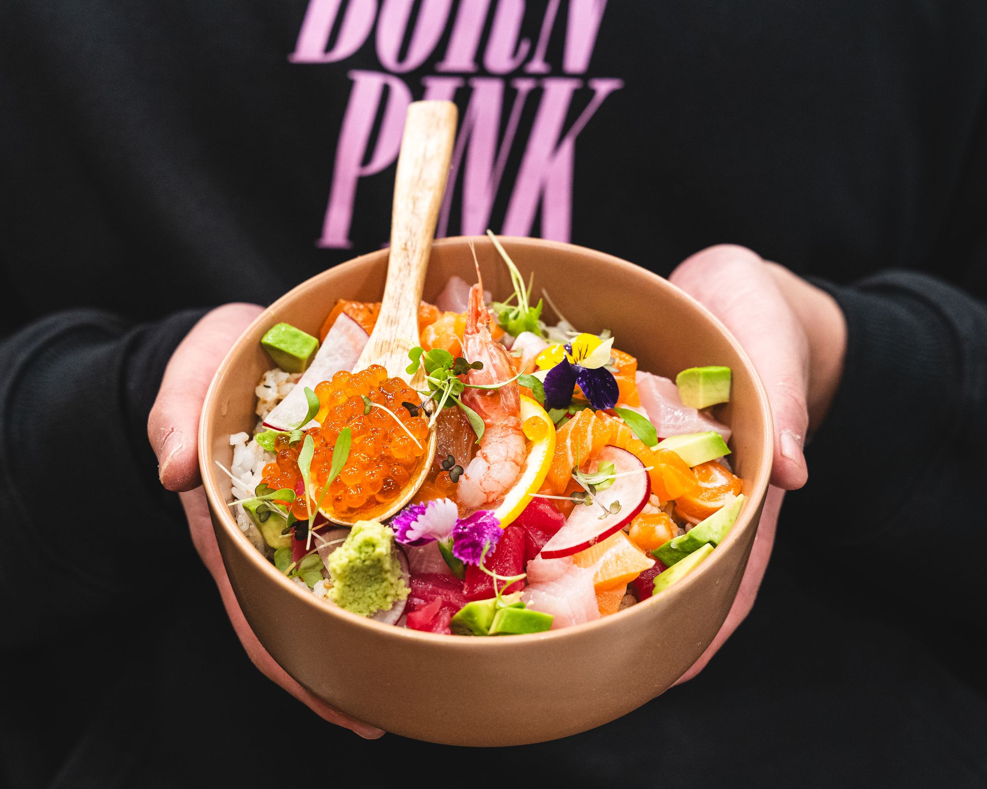 Hand holding bowl with diced sashimi (ikura, amaebi, salmon, tuna and yellowtail)