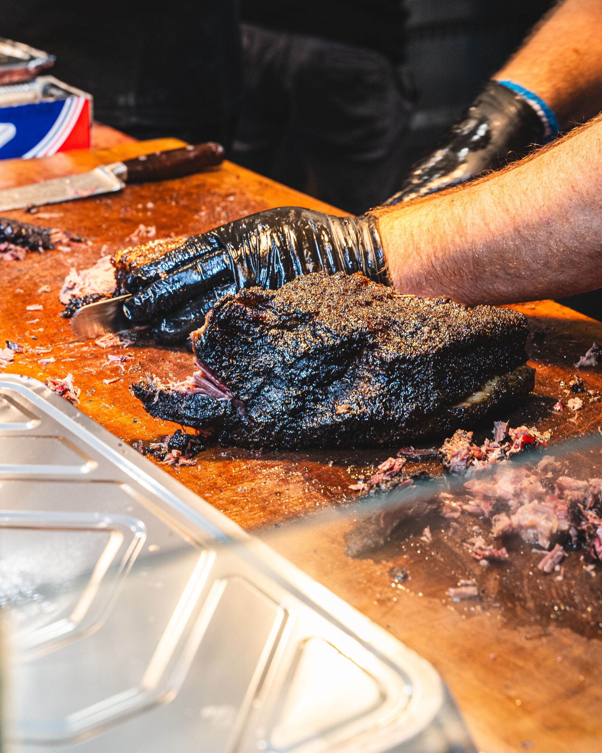 Black gloved hand cutting brisket