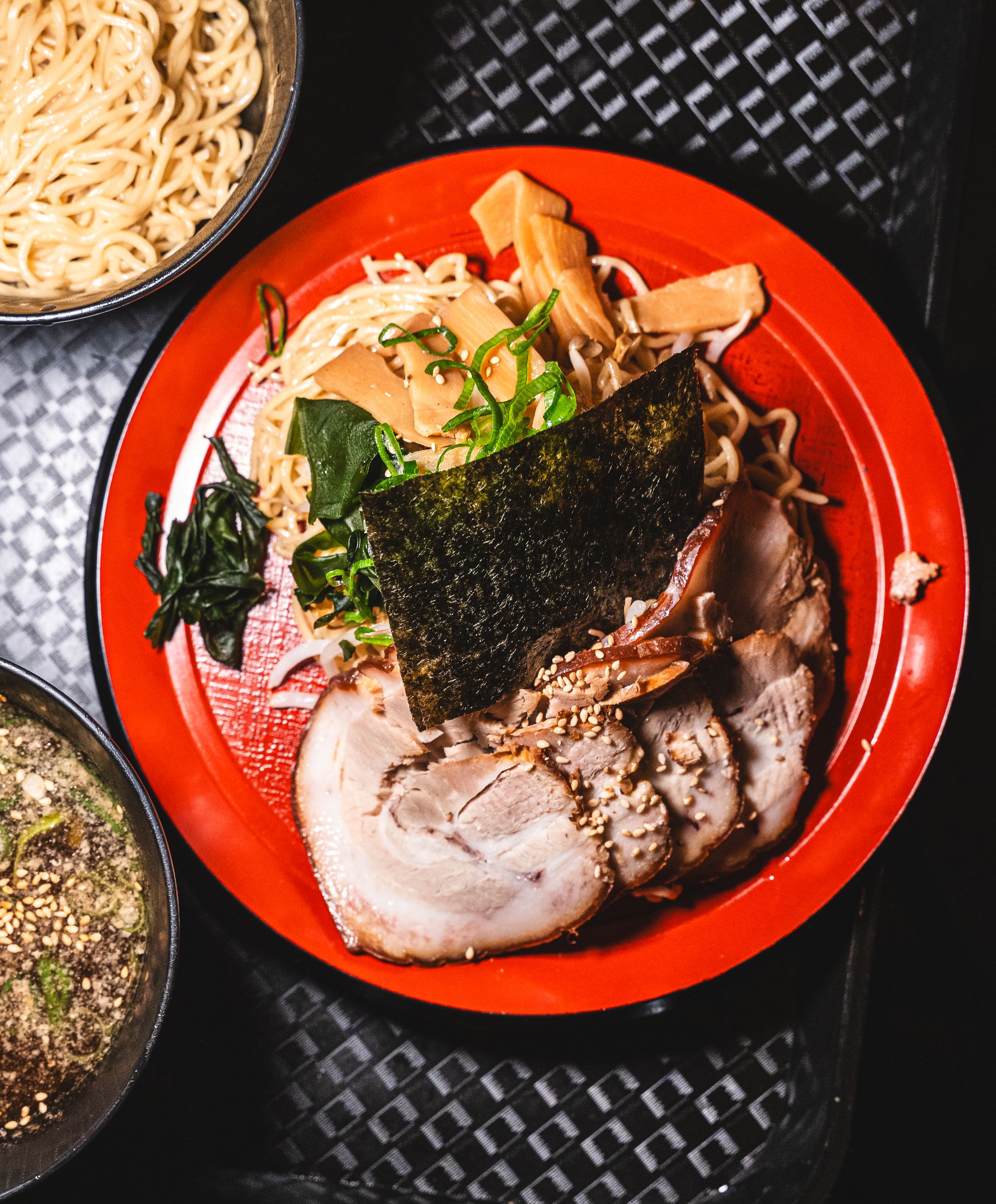 Top down shot of plate with ramen noodles, spring onions, seaweed and chashu