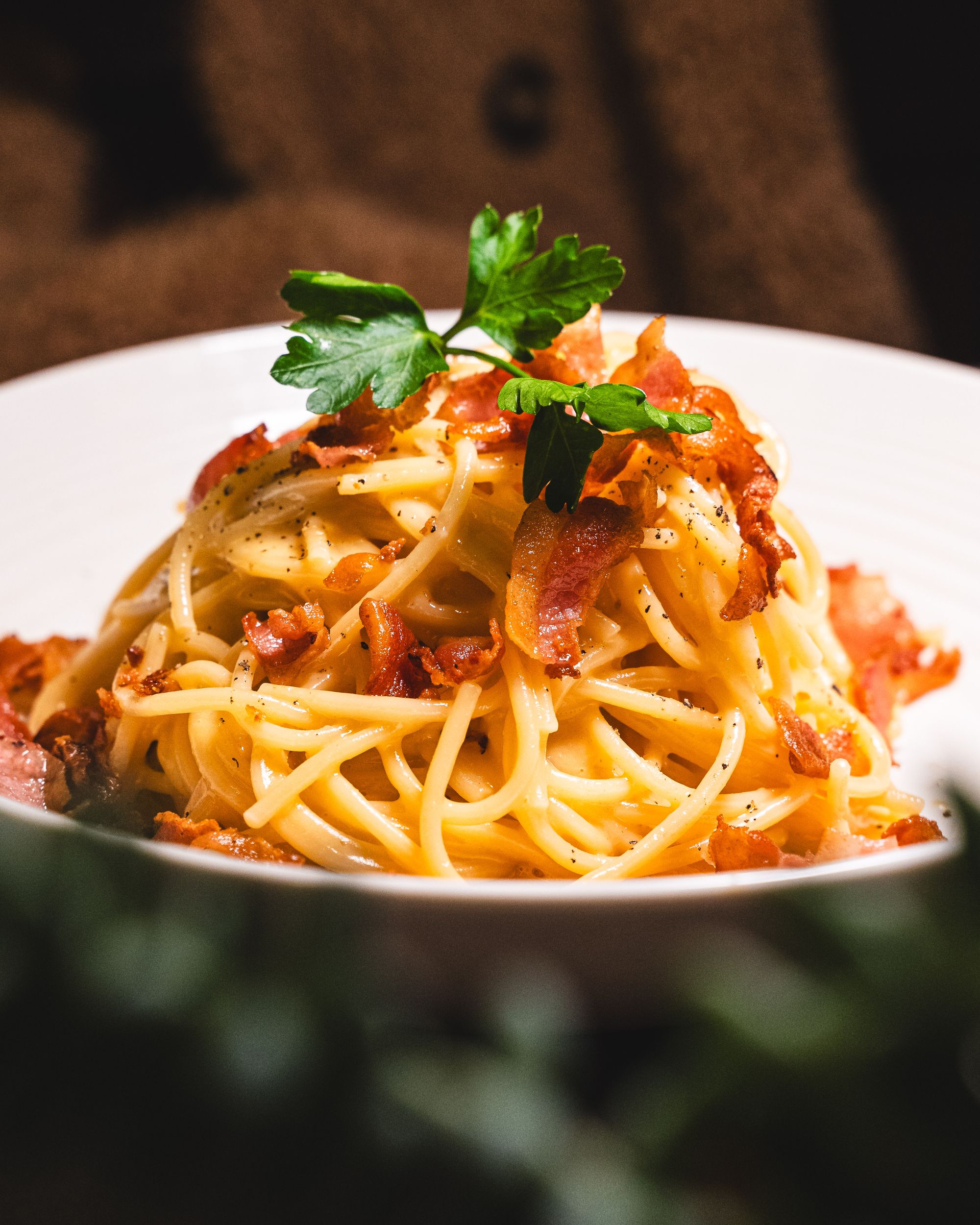 Close up of spaghetti carbonara with guanciale and parsley as garnish