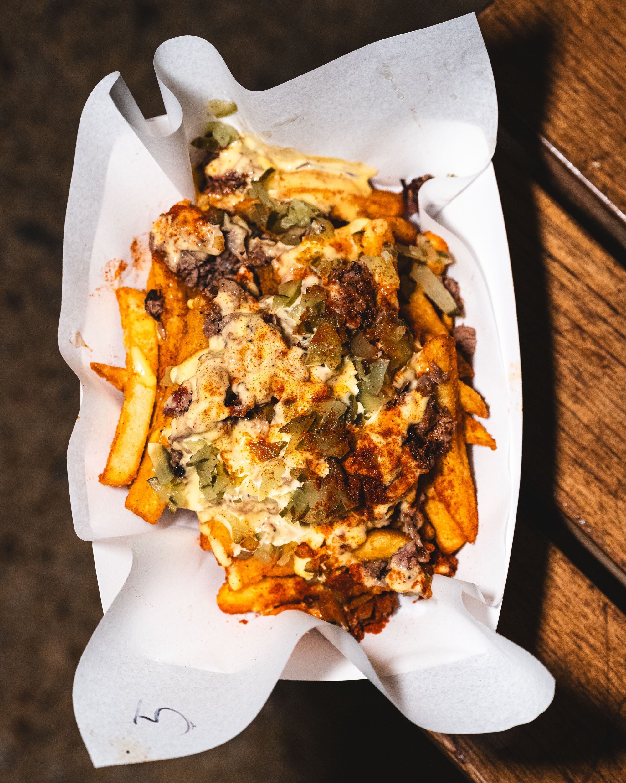 Top down shot of dirty fries with queso, fries, pickles and chopped brisket