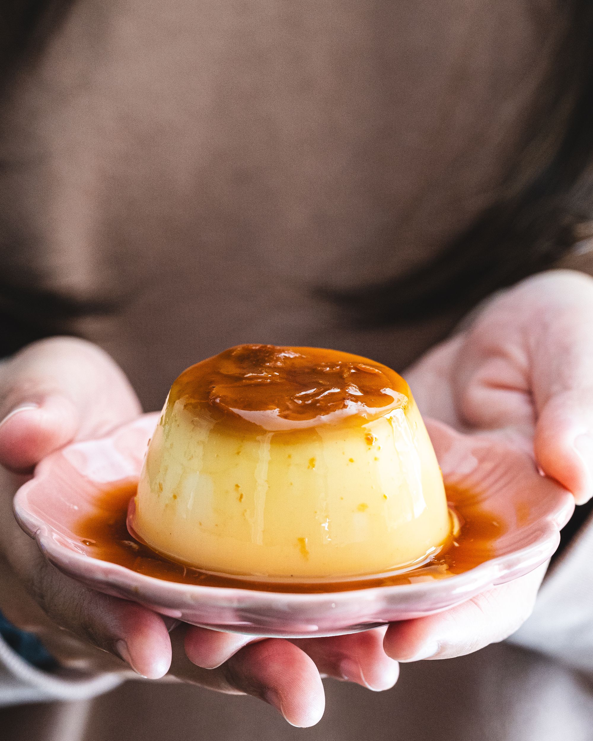 Hand holding Japanese pudding on a small flower shape plate