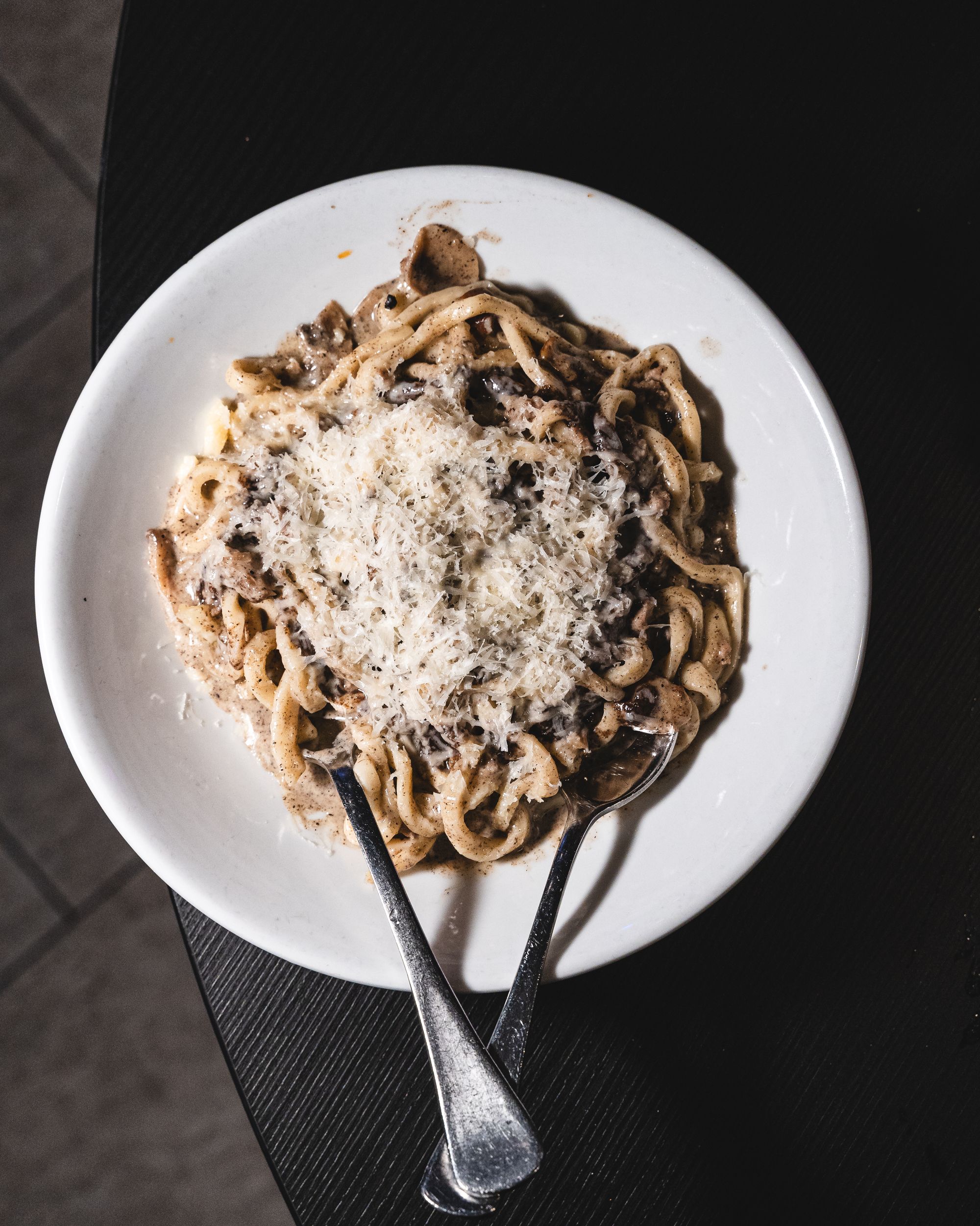 Top down shot of pasta on a round plate with cheese shaved on-top