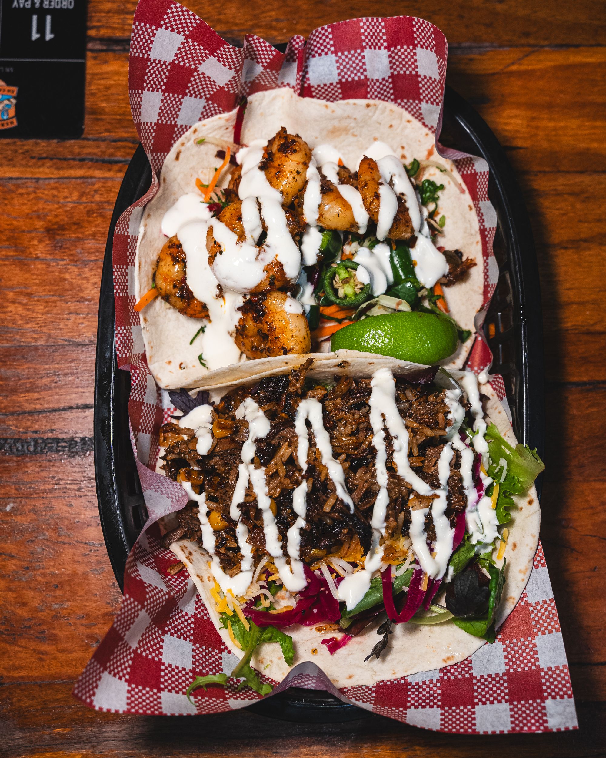 Top down shot of king prawn tacos in soft tortillas, with ganish of lime and coriander