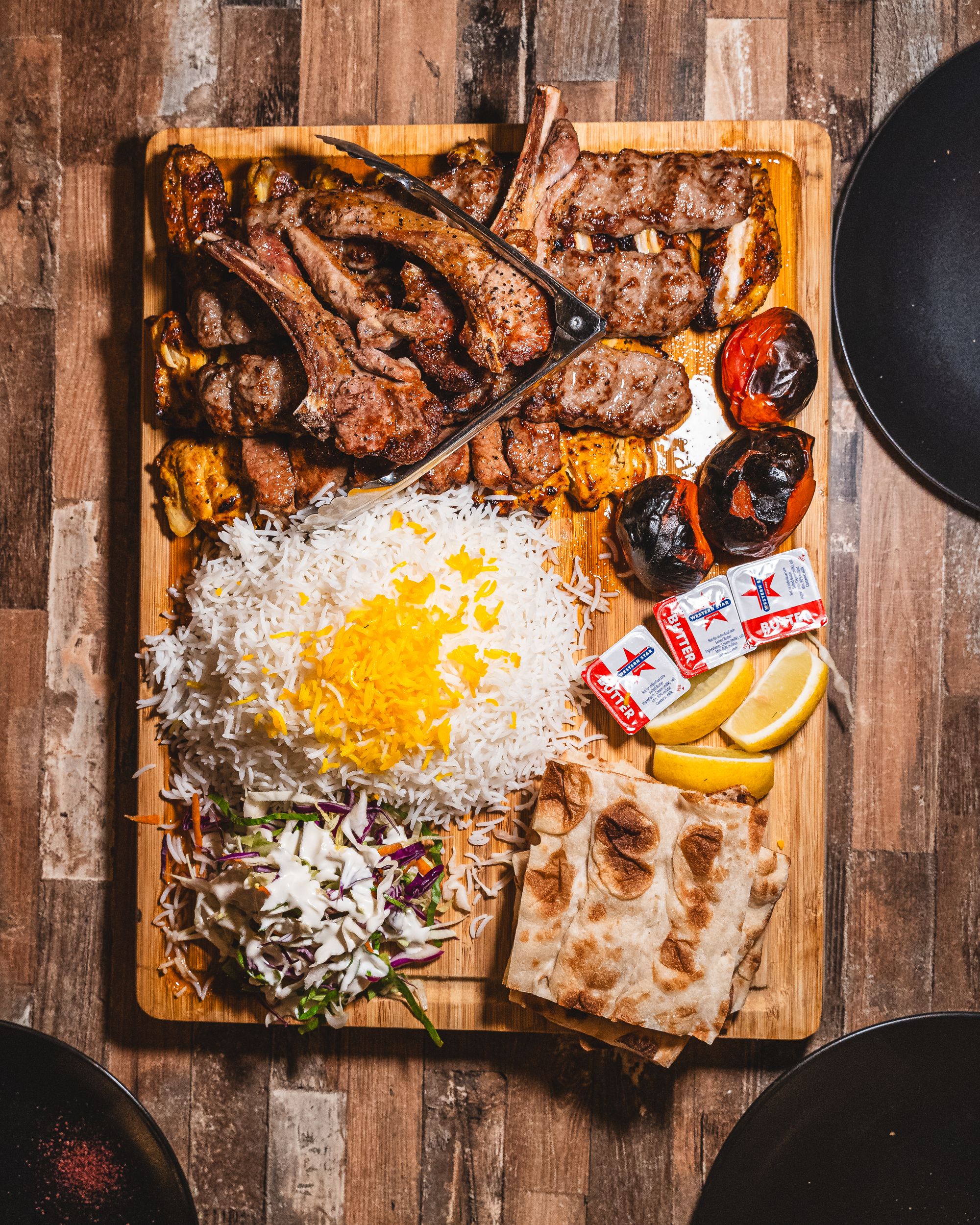 Top down of meat platter with rice, salad, lemon, char-grilled tomato, and different meats