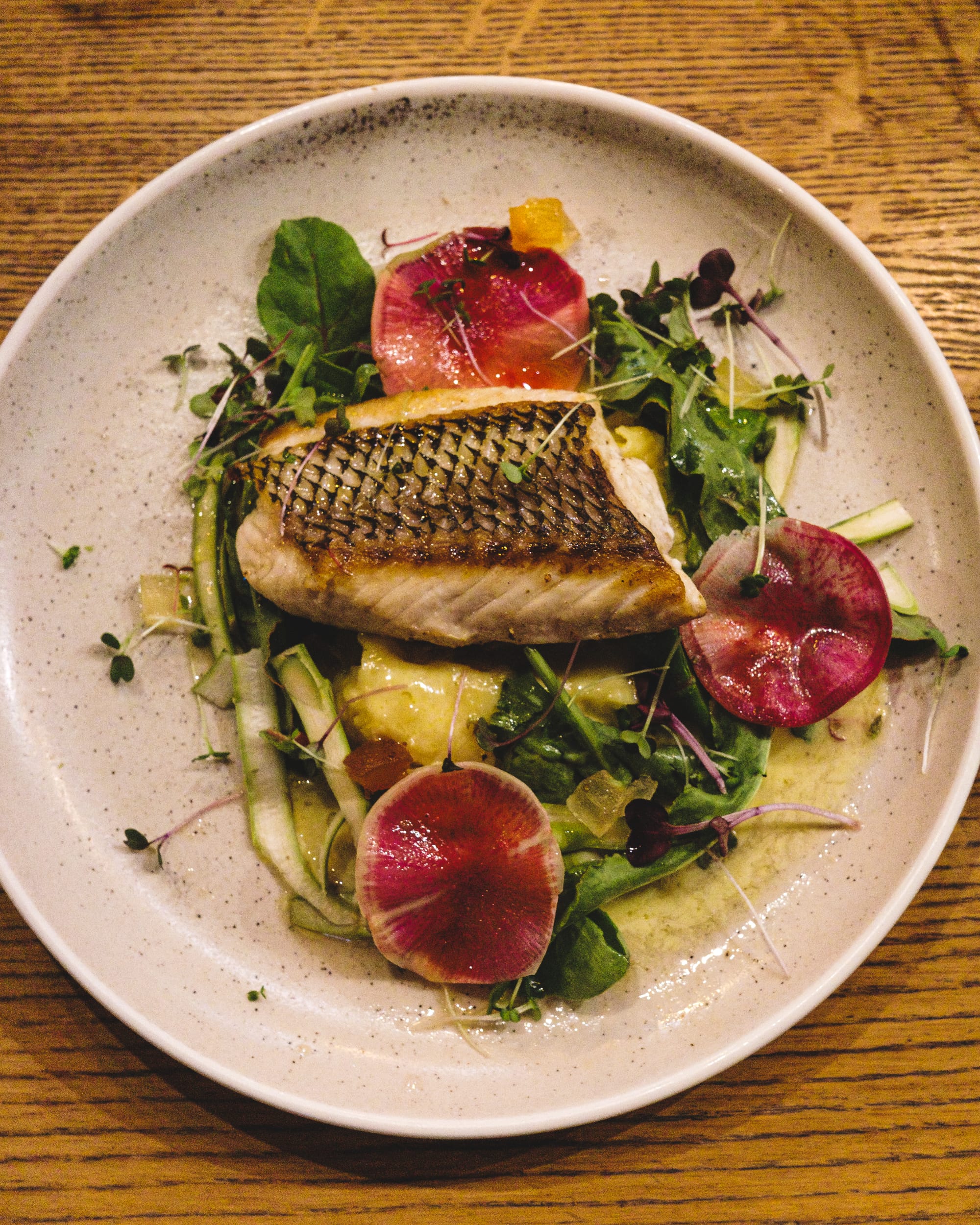 Top down of fish with mash, mustard fruits, asparagus, radish and kohlrabi