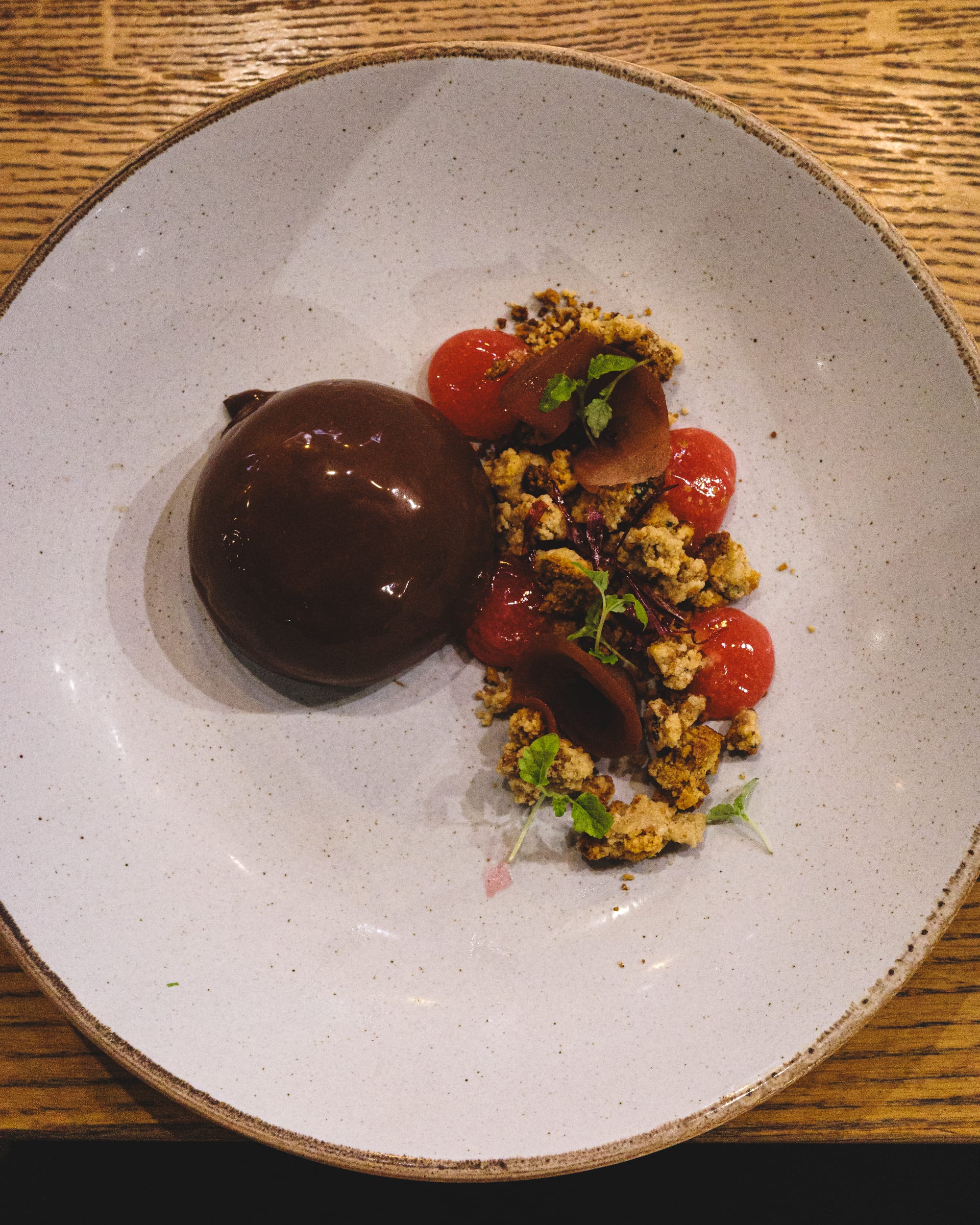 Top down shot of chocolate dome with crumble, pear and rhubarb gel