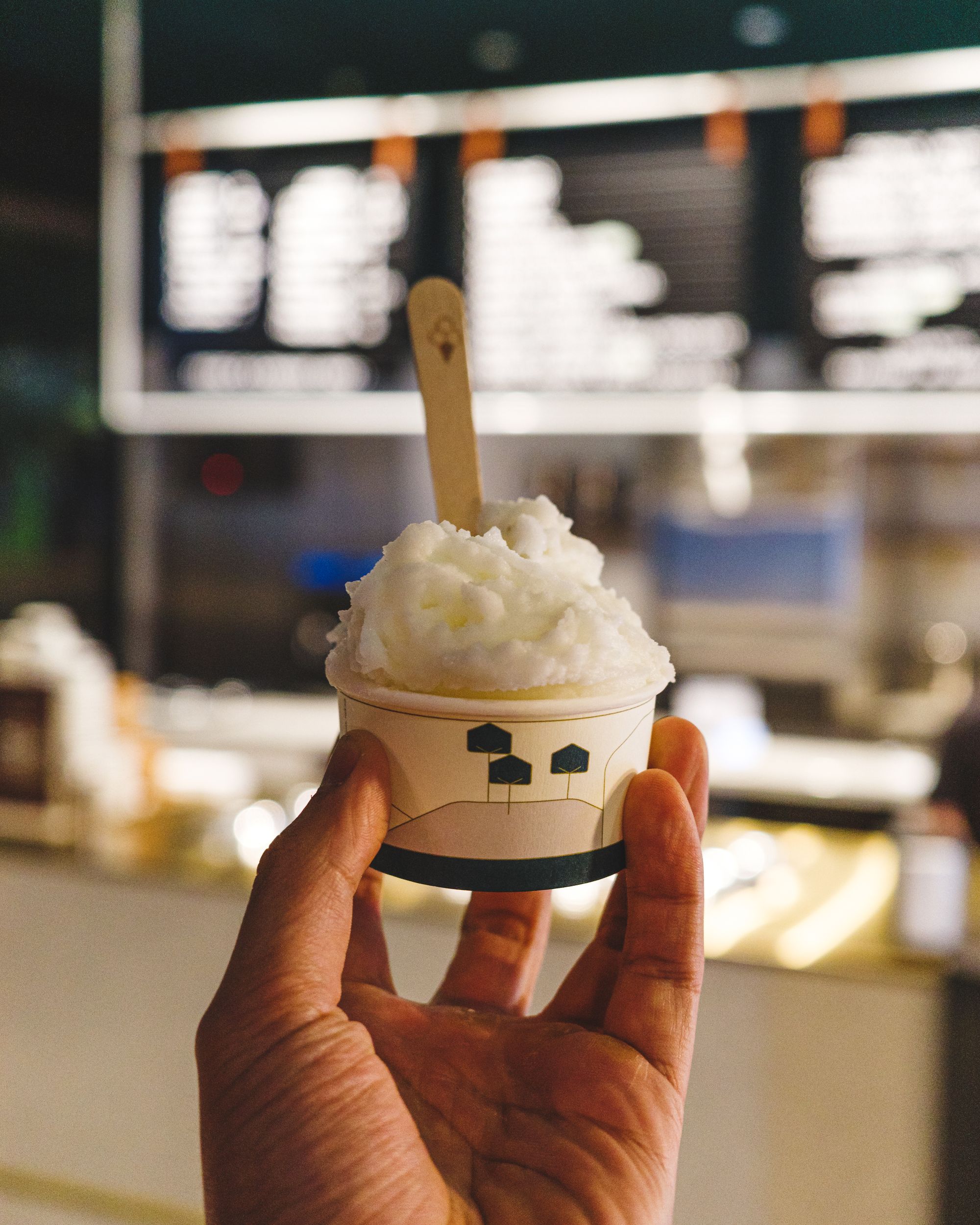 Hand holding a scoop of lemon sorbet in a cup