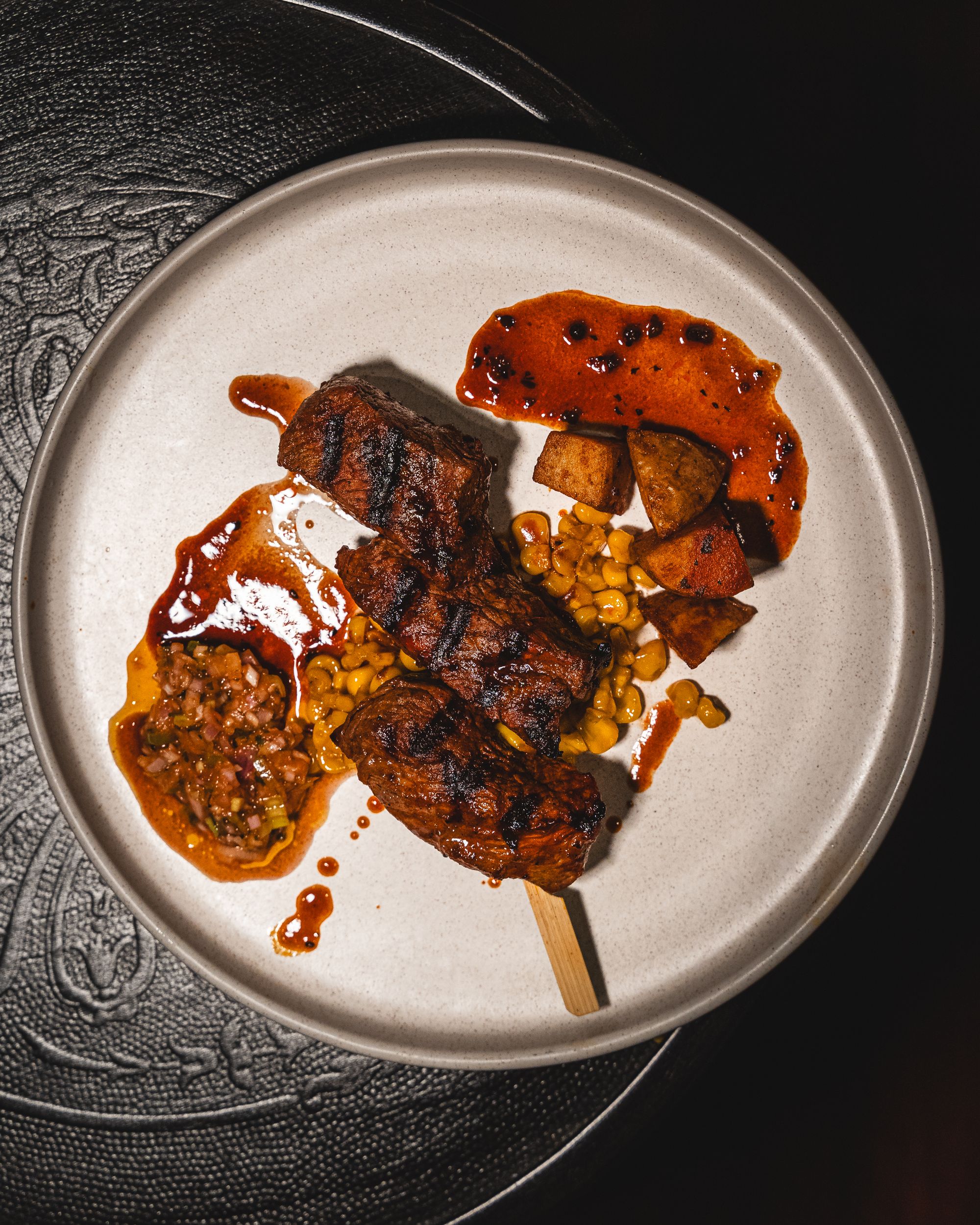 Top down shot of beef anticucho with corn and potato