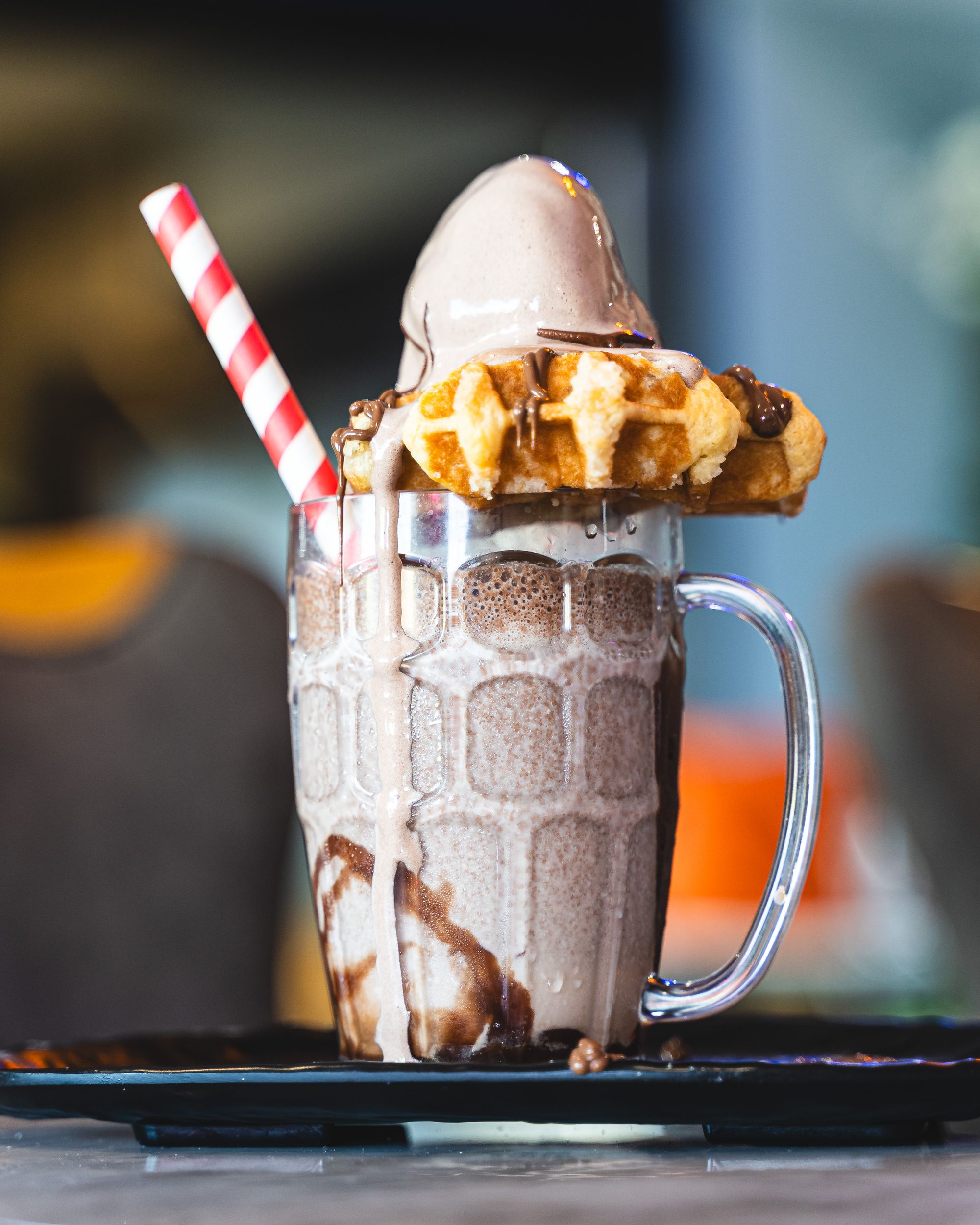 Close up shot of chocolate milkshake with a waffle and ice-cream served on-top