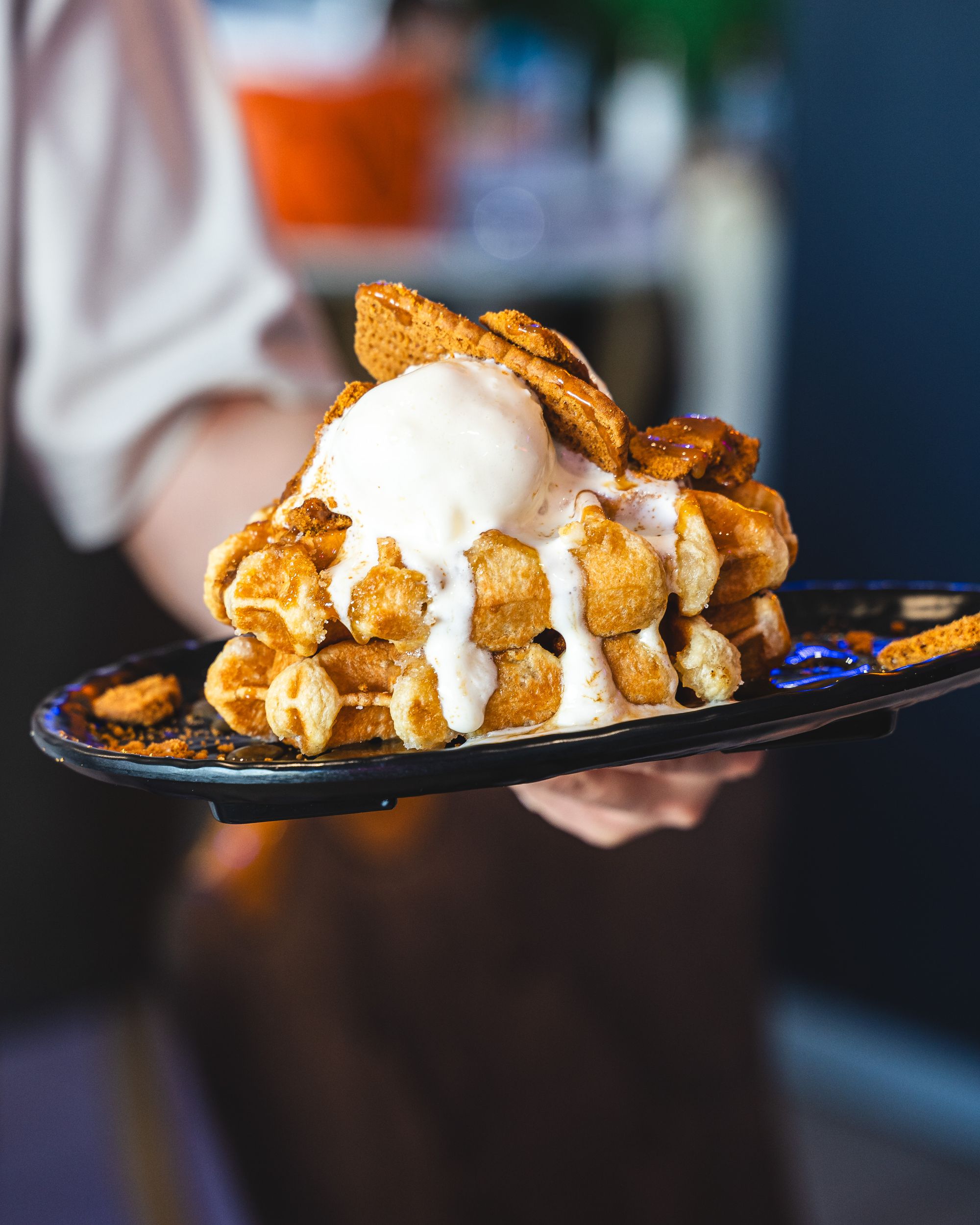 Hand holding a waffles stacked three high with Biscoff biscuits and ice-cream