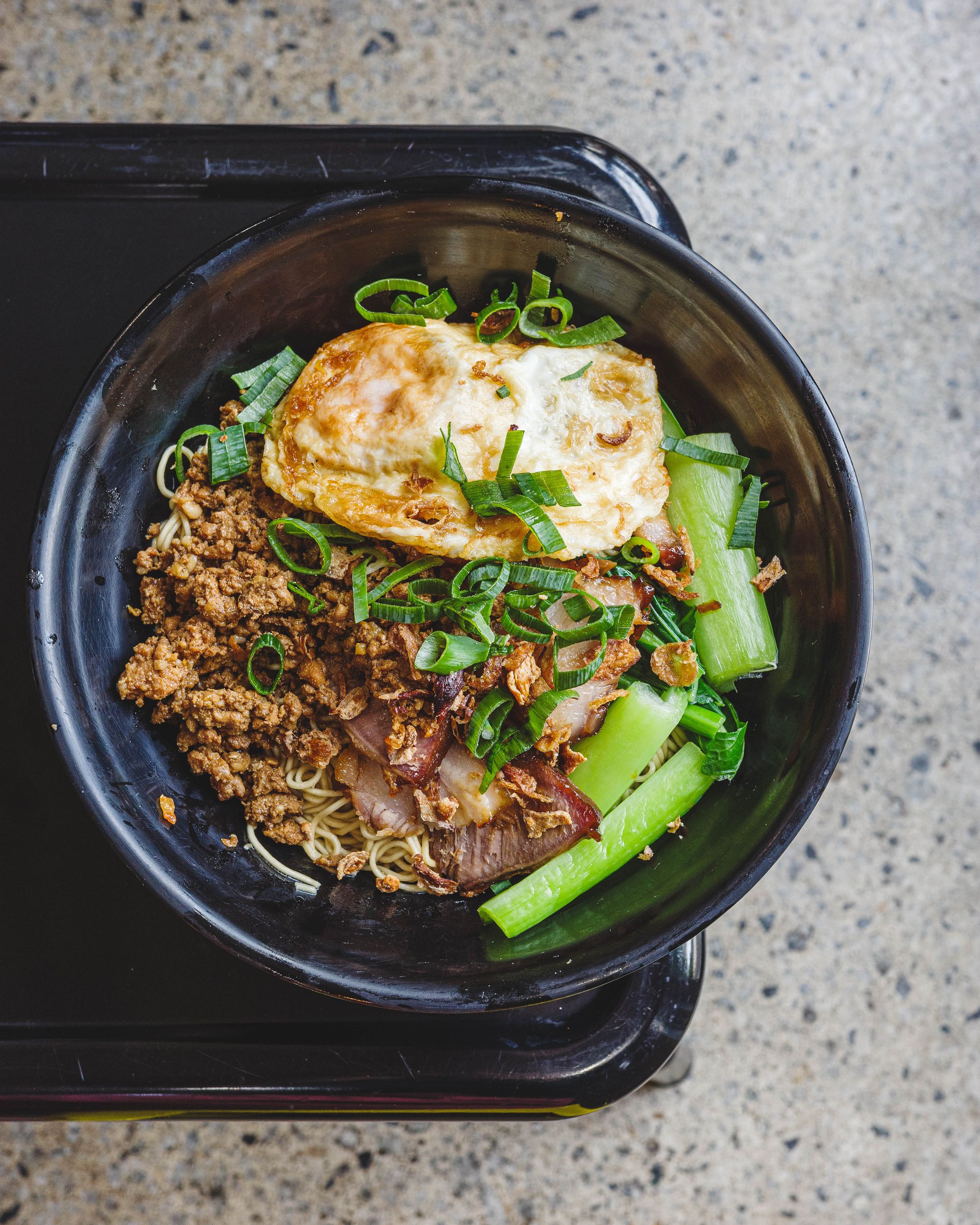 Top down shot of noodles, mince beef, Chinese vegetables and a fried egg