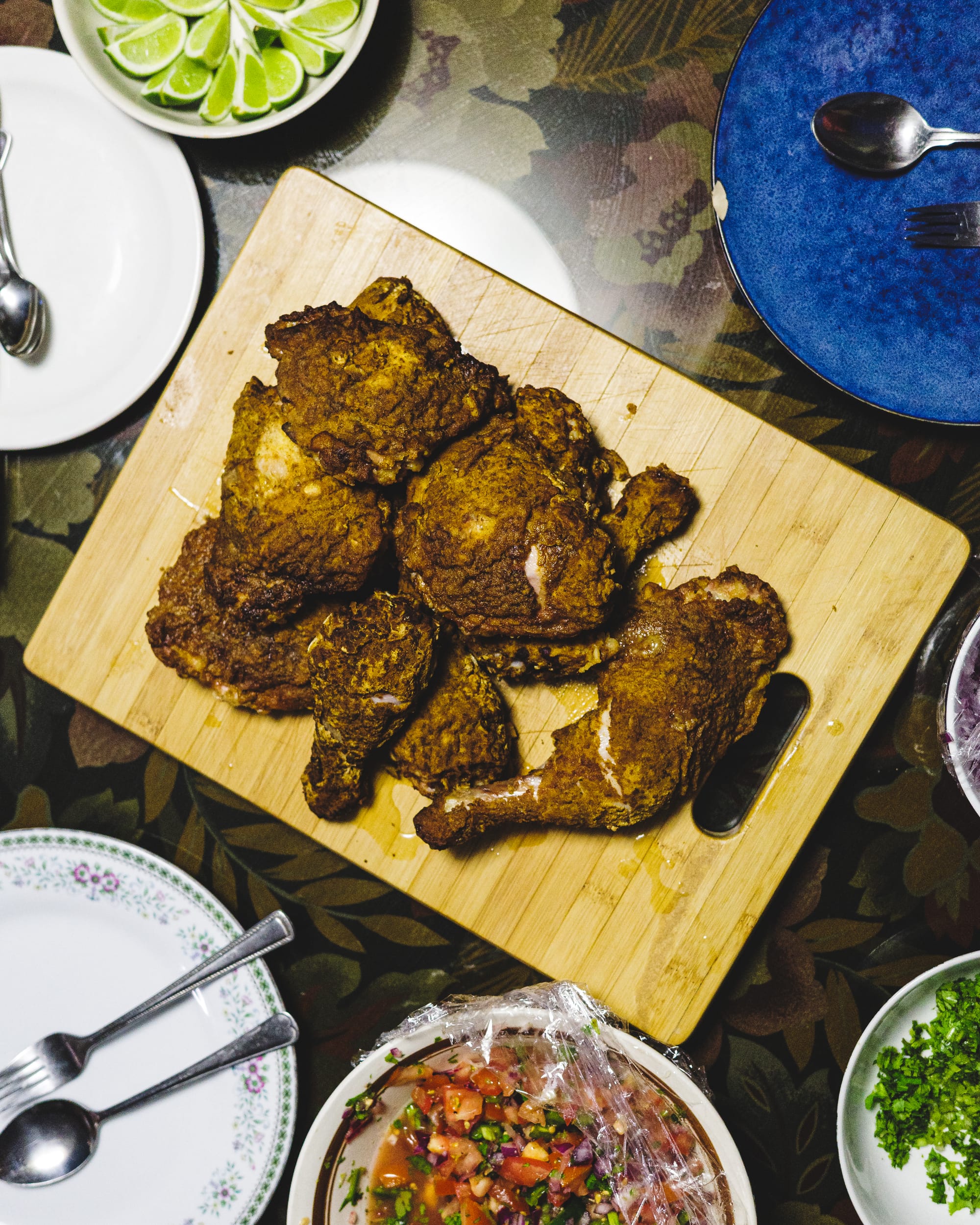 Top down shot of air fried chicken piled on-top of a wooden chopping board