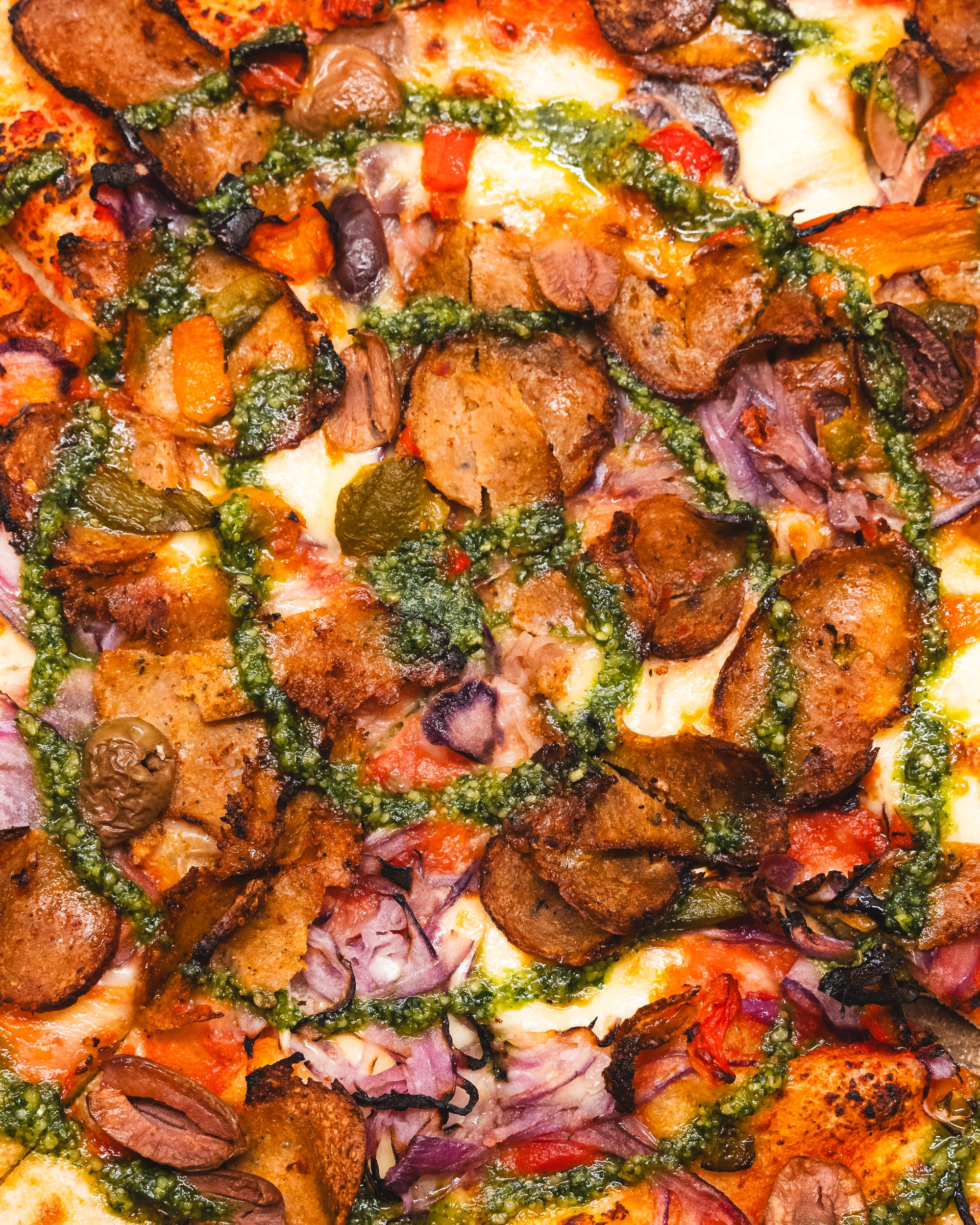 Close up of pizza with pesto, tomatoes, onion