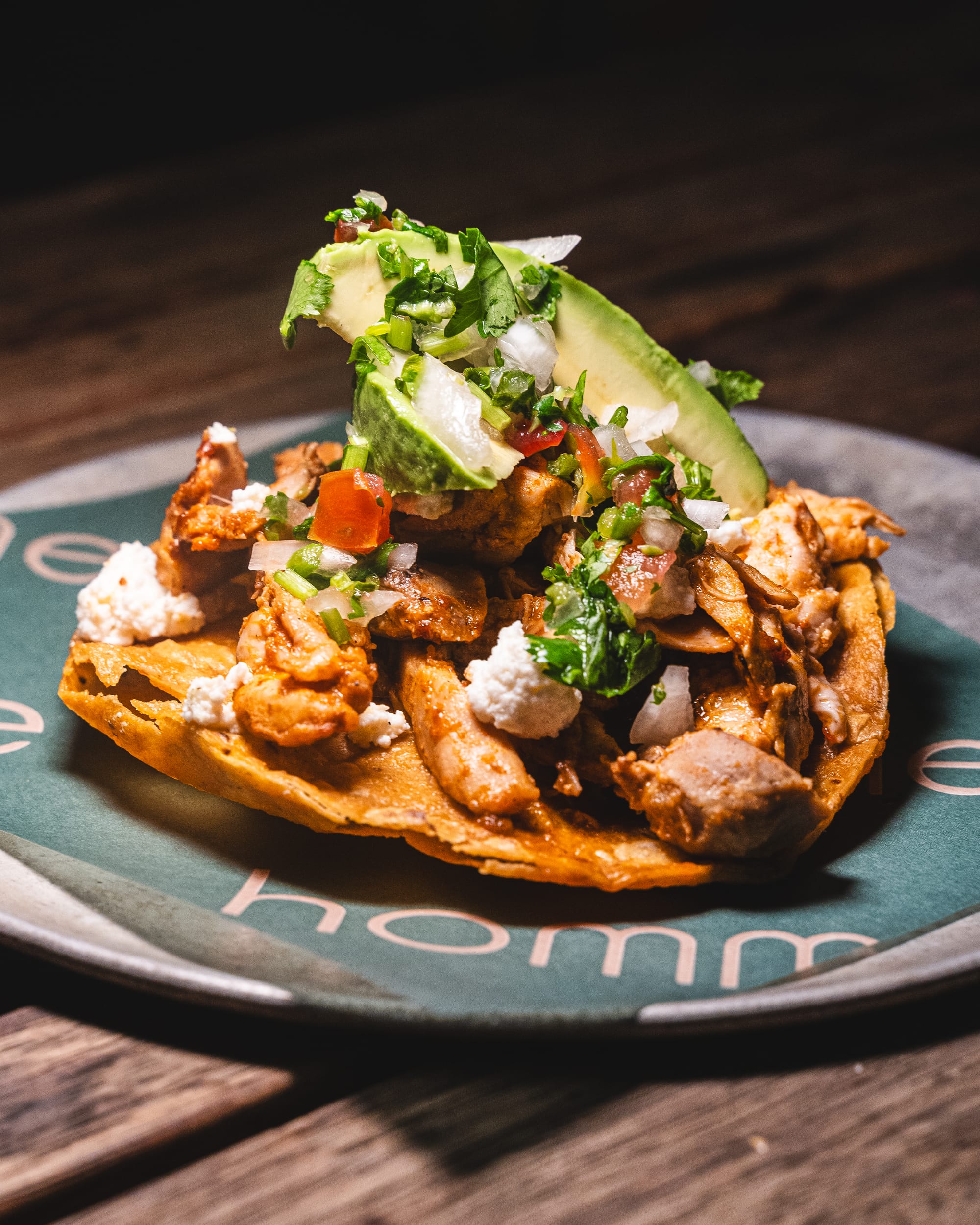 Close up of tostada with chicken, avocado and herbs