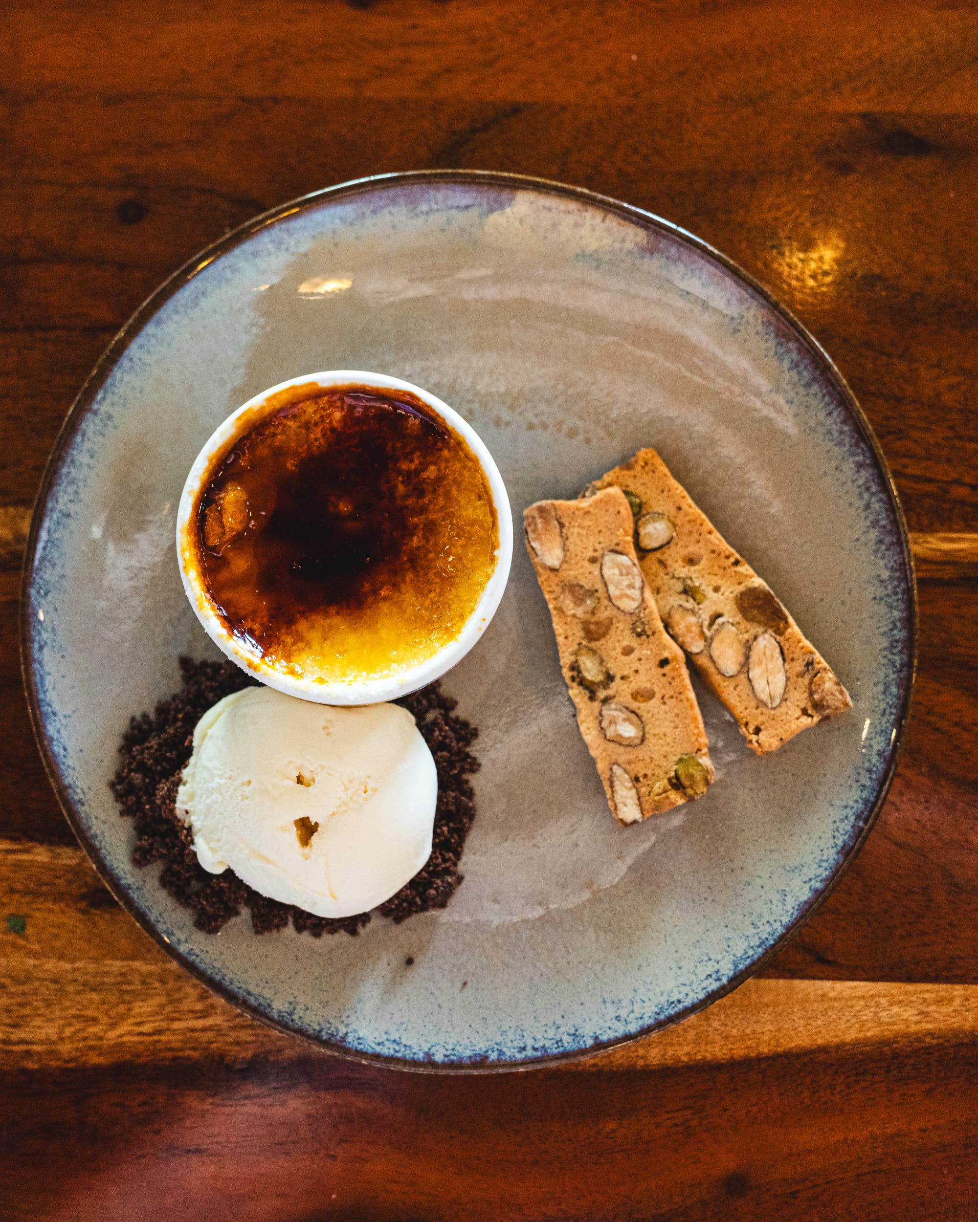 Top down shot of creme brulee with ice-cream and biscotti