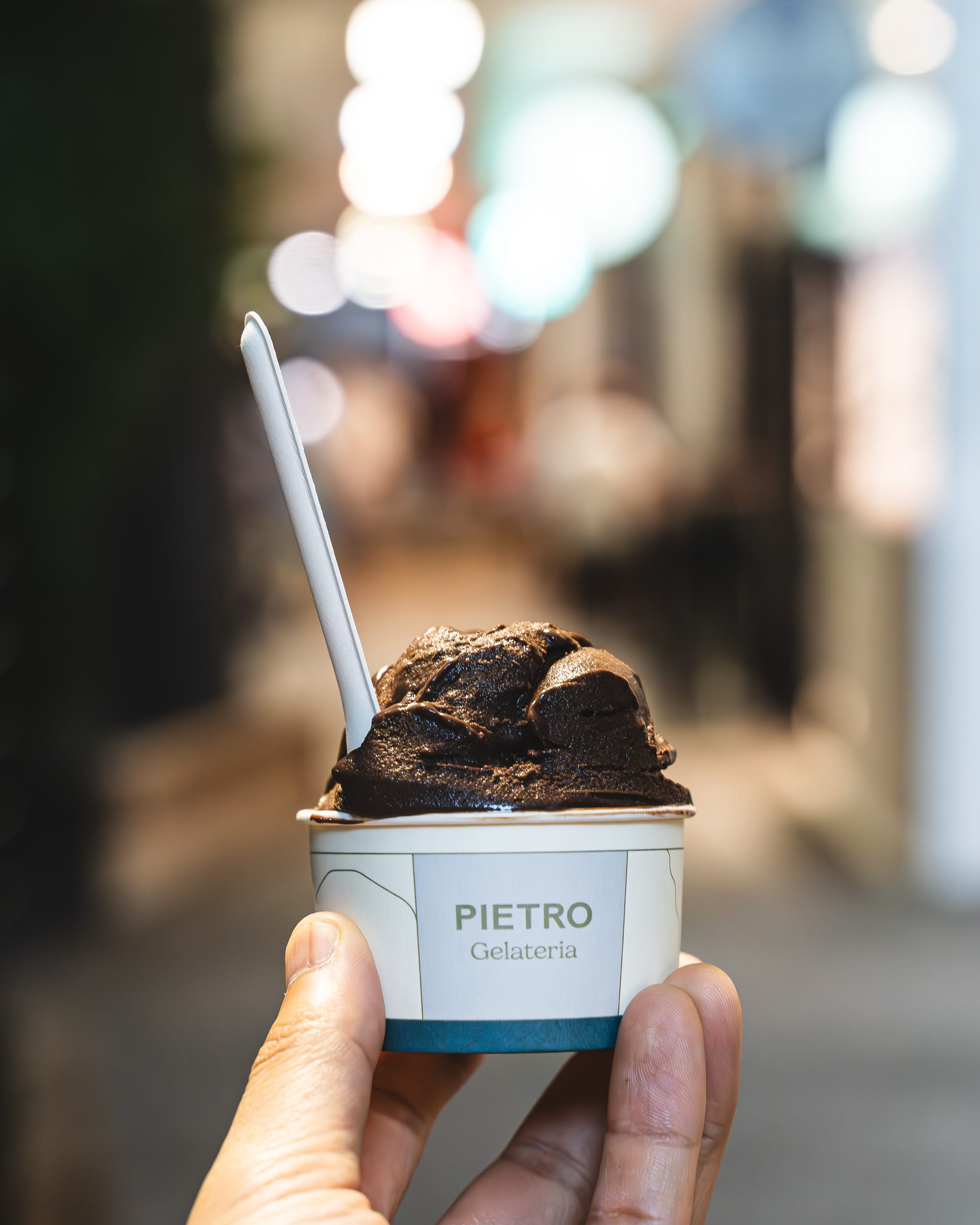 Hand holding cup of gelato with spoon