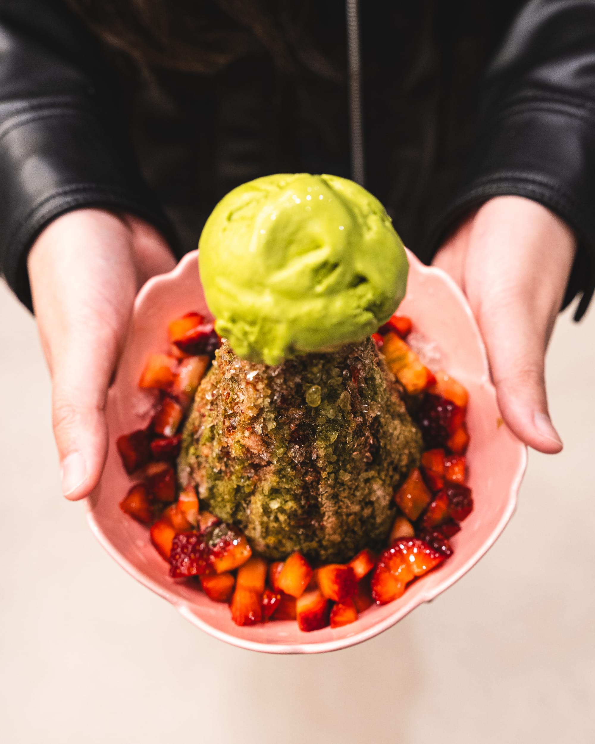 Hand holding shaved ice dessert with cubed strawberry and ice-cream on-top