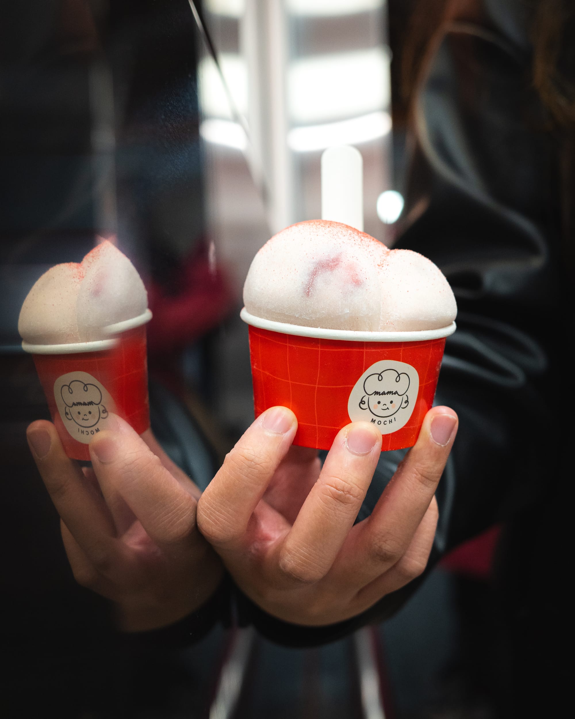 Hand holding ice-cream mochi in a red paper cup