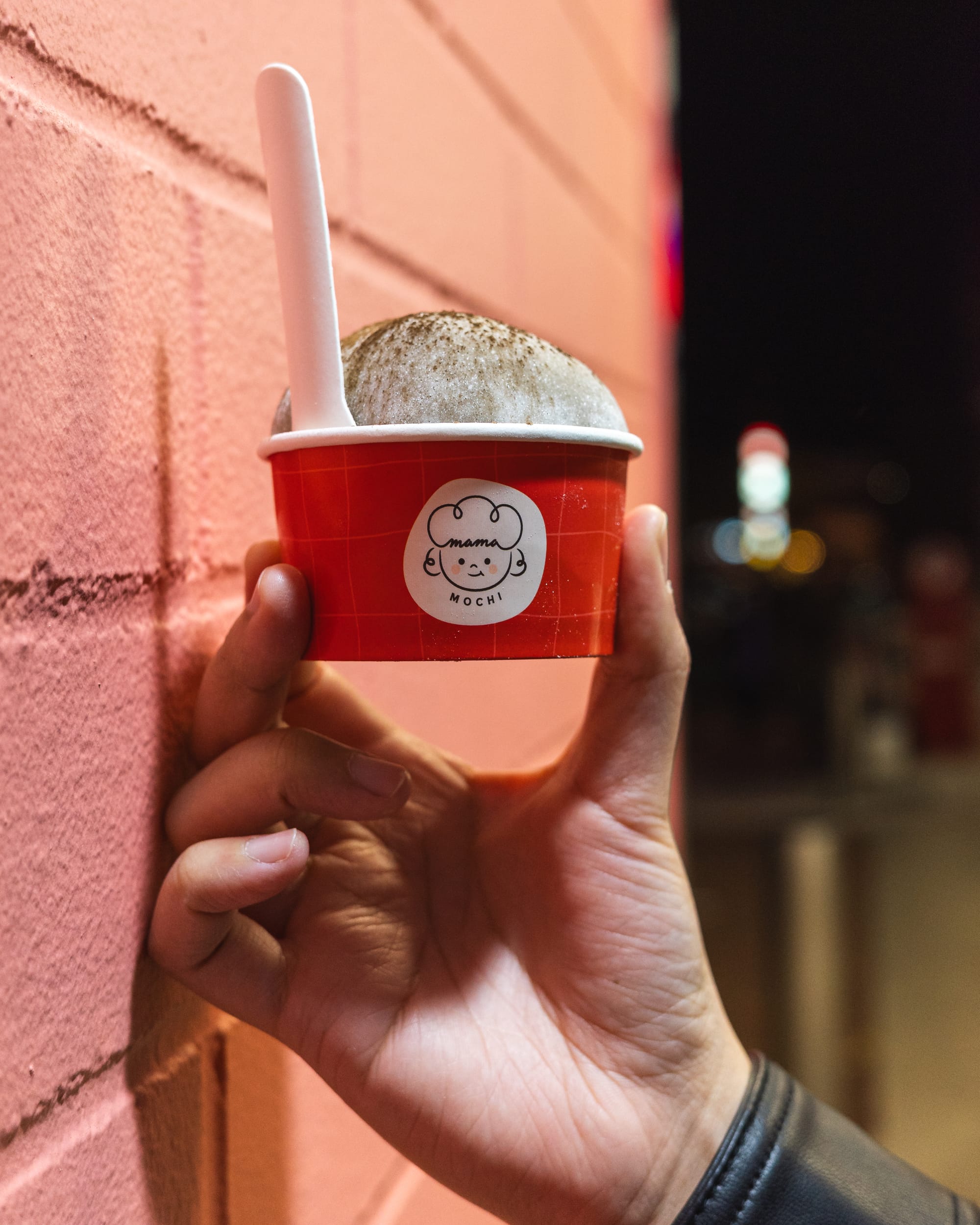 Hand holding ice-cream mochi in a red paper cup