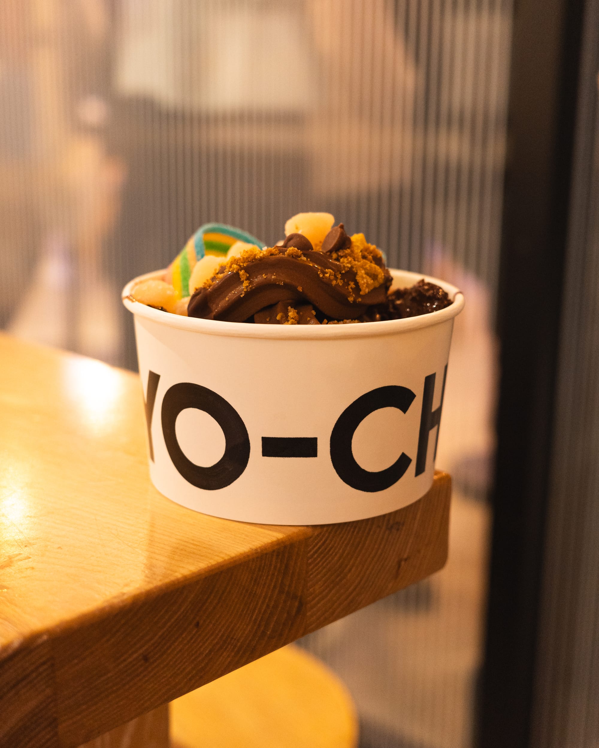 Close up of froyo in a paper bowl with choc chips, sour strap and corn flakes