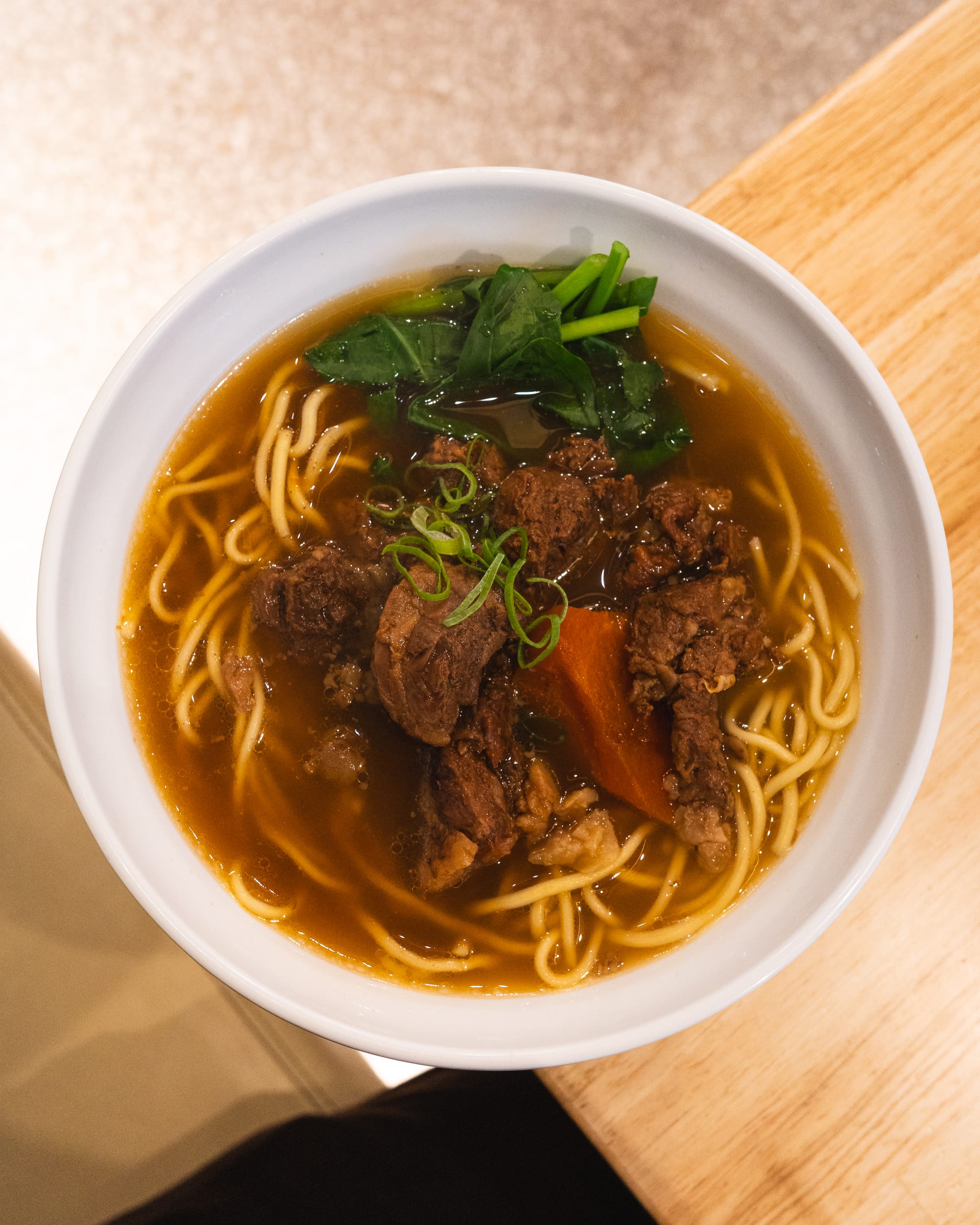 Top down shot of beef brisket noodles with Chinese vegetables, carrot and noodles