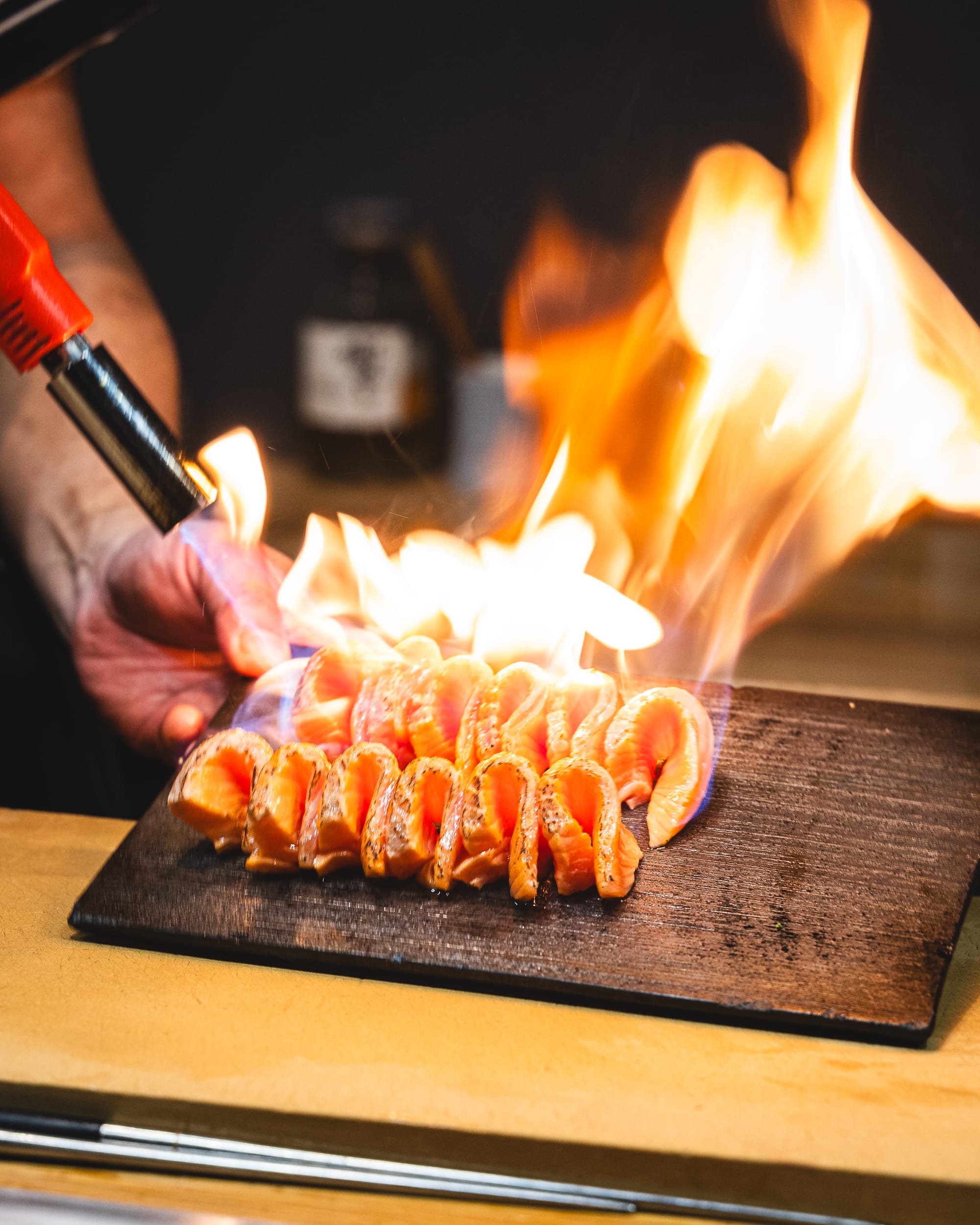 Closeup of blowtorch flame searing salmon sashimi