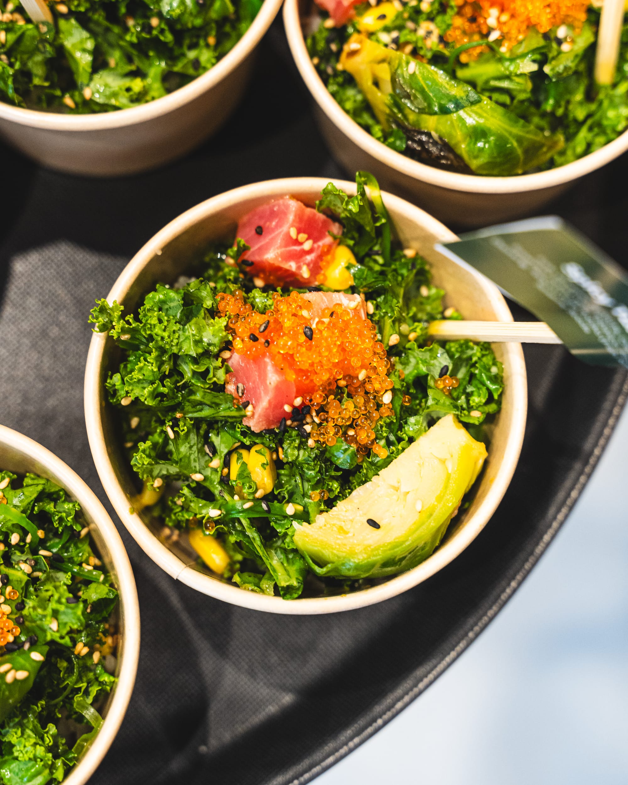 Top down shot of poke bowl with tobiko, brussel sprout, kale, tuna and seasame seeds