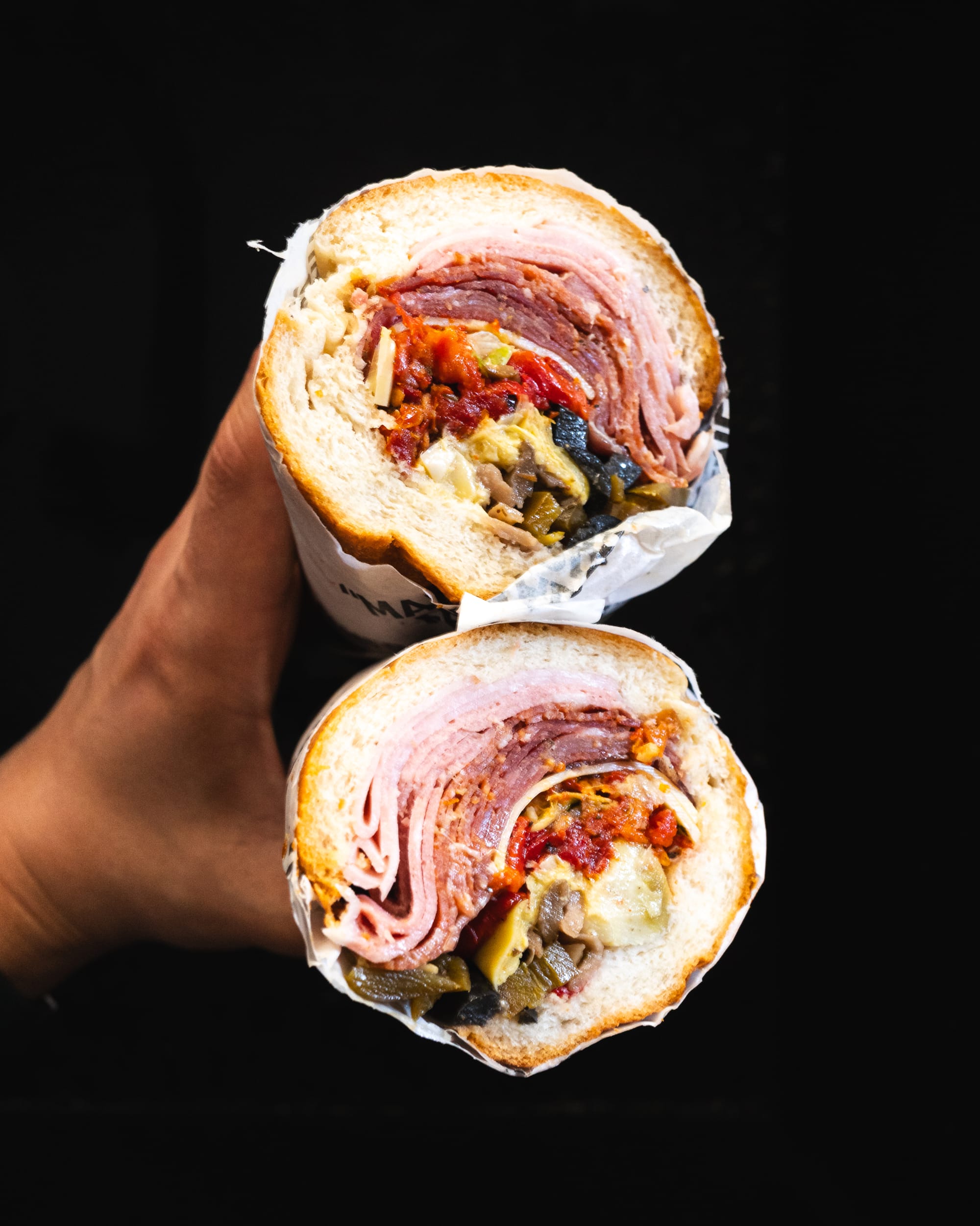 Close up of hand holding an Italian sandwich with antipasto 