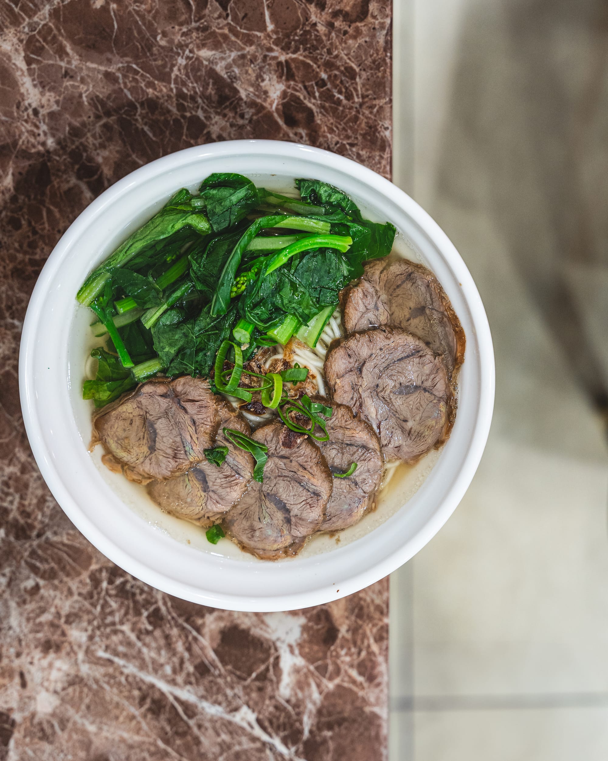 Top down shot of noodles with thin beef slices and vegetables