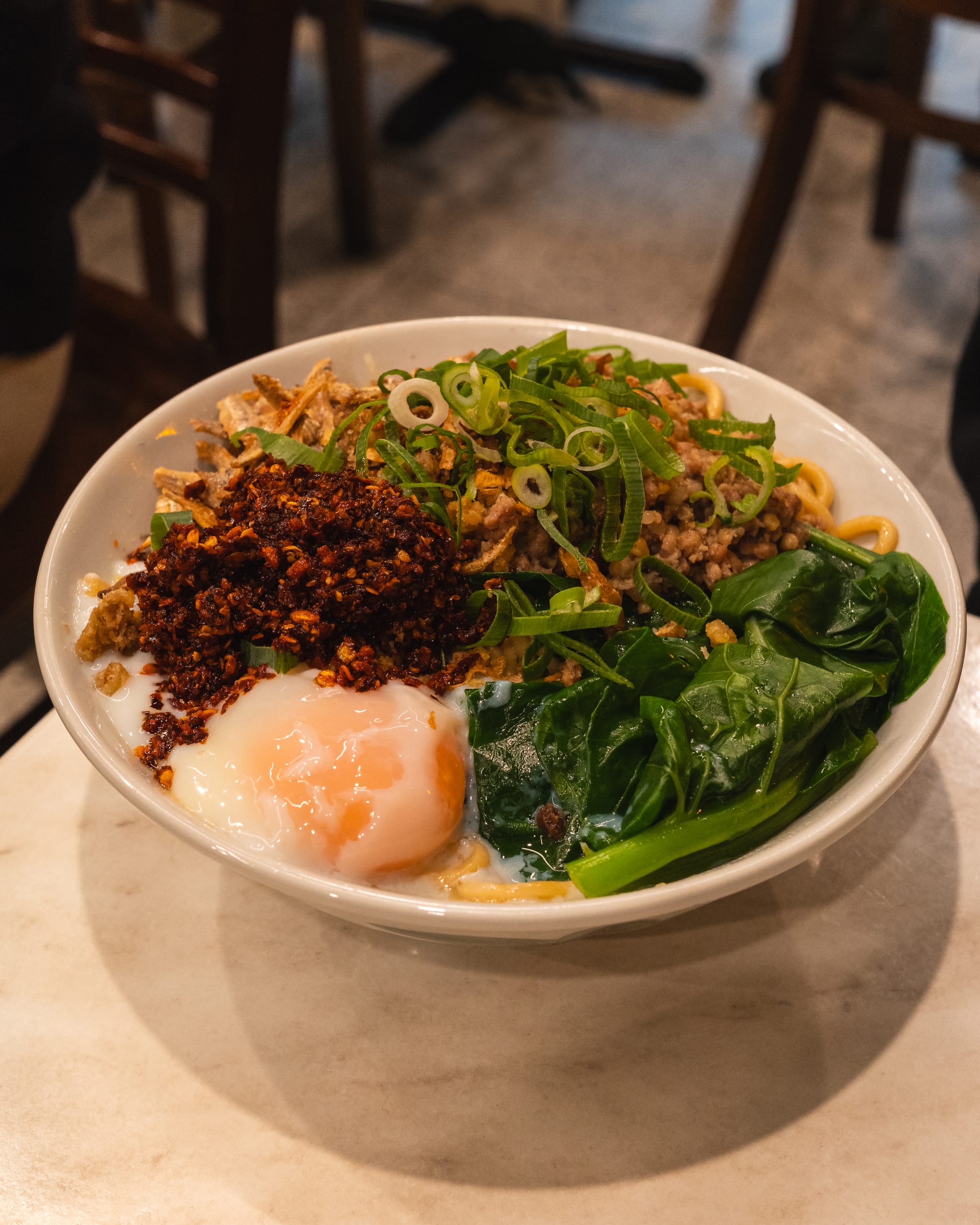 Close up of pan mee with sous vide egg, chilli, spring onions and vegetables