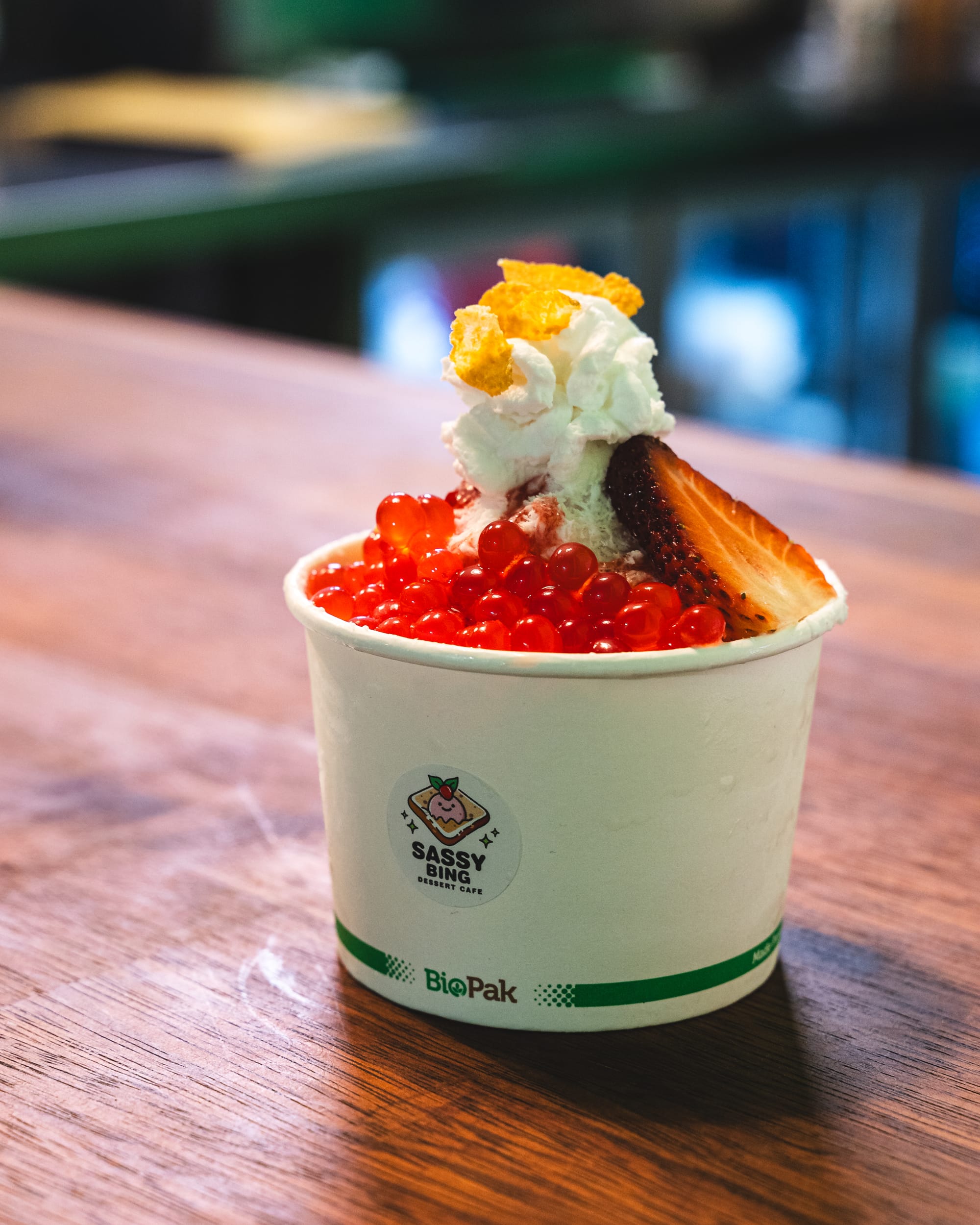 Close up of bingsu served in a paper cup with jelly balls and strawberry