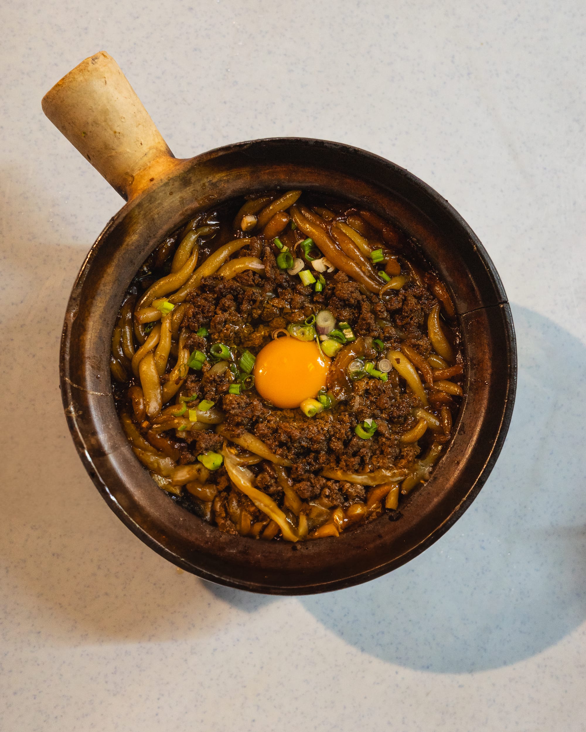 Claypot with noodles, mince meat, spring onions and egg yolk