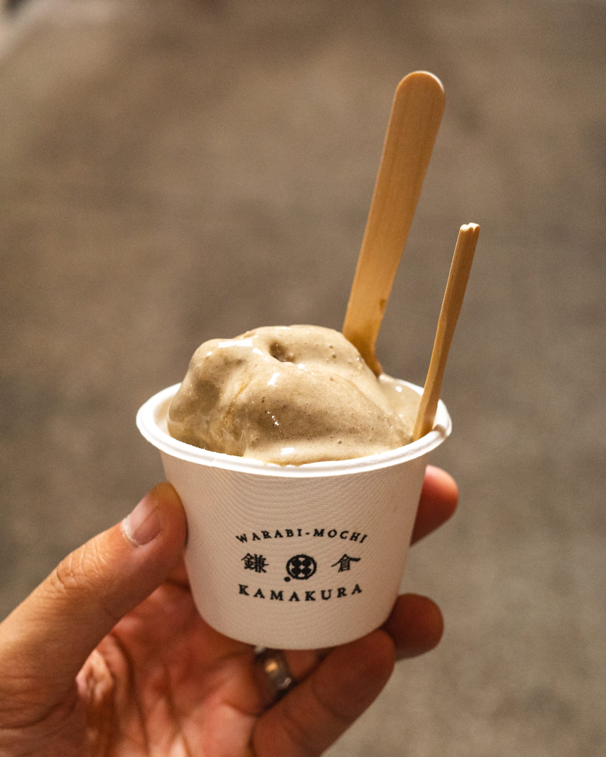 Hand holding a paper cup with hojicha ice-cream and mochi