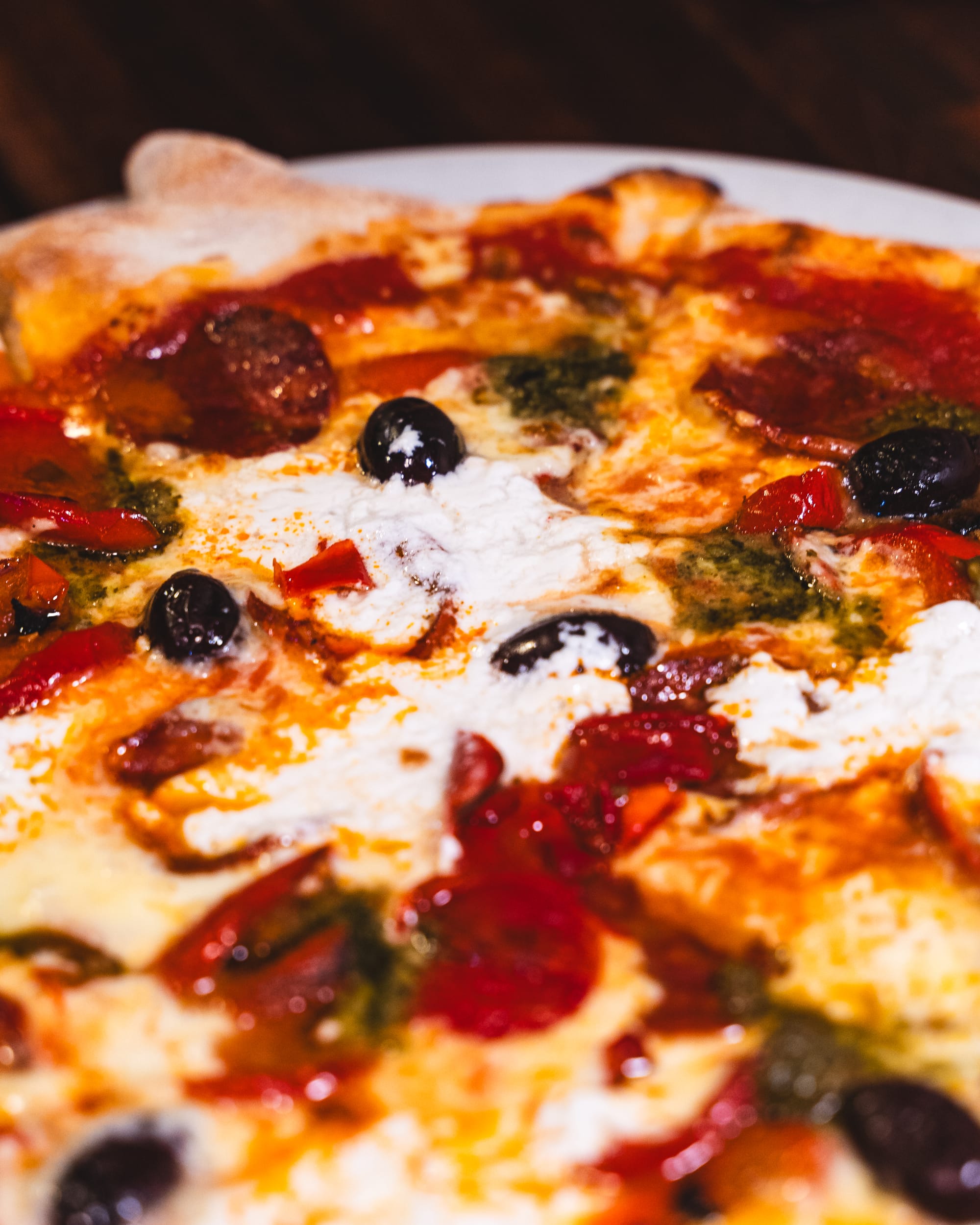 Close-up of shot of pizza with melted cheese, salami and olives