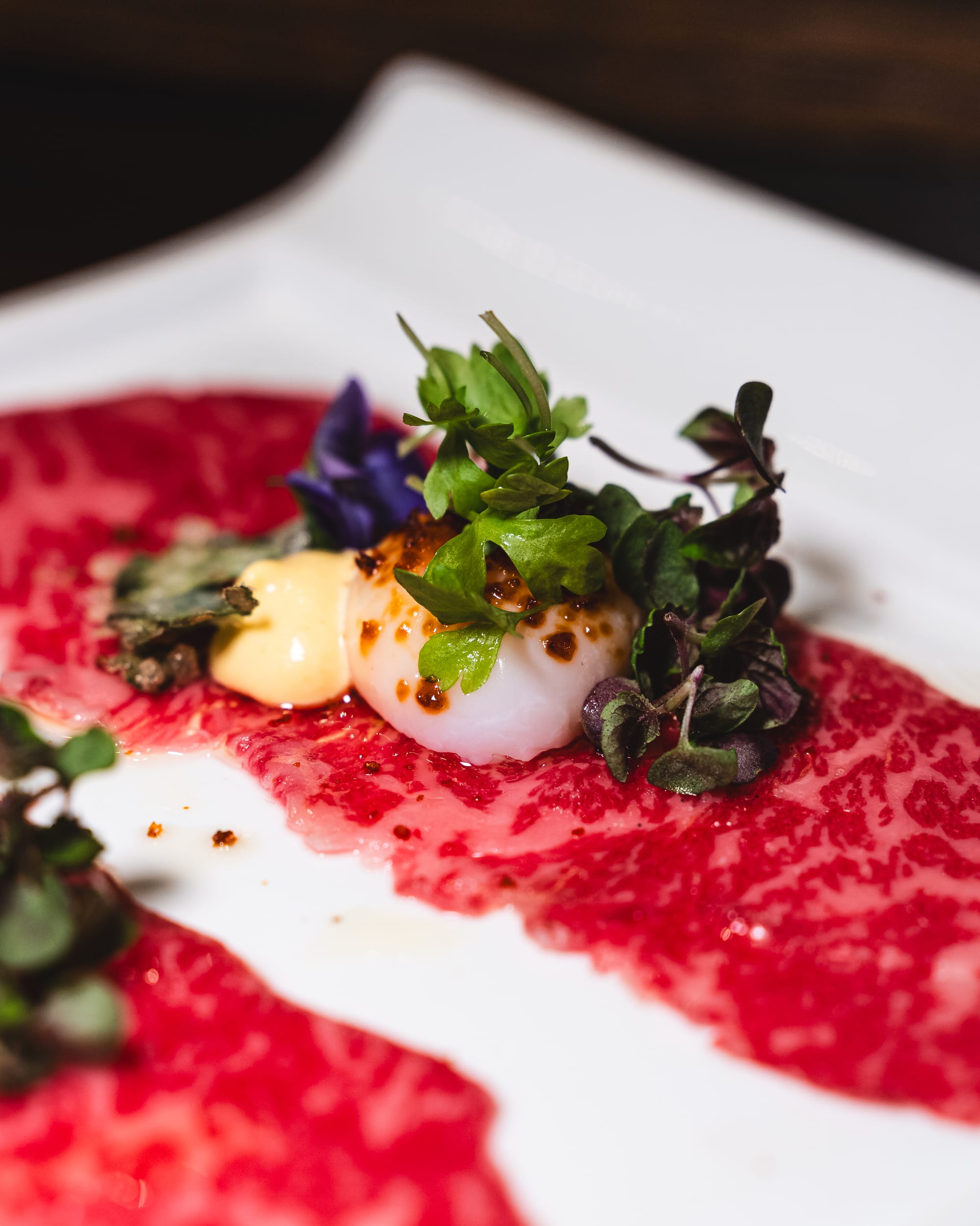 Close up of thinly sliced wagyu beef with aioli, microgreens and quail egg