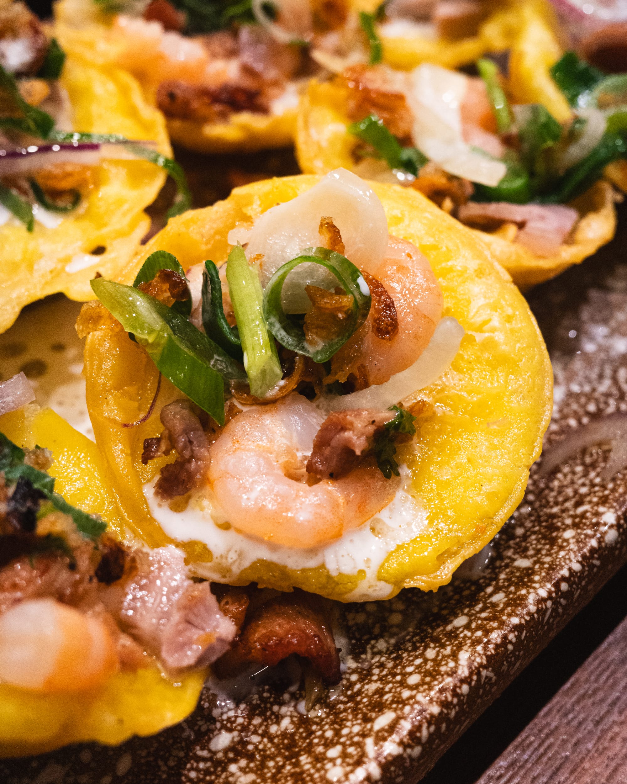 Close up of mini Vietnamese savoury pancake showing spring onion and prawn