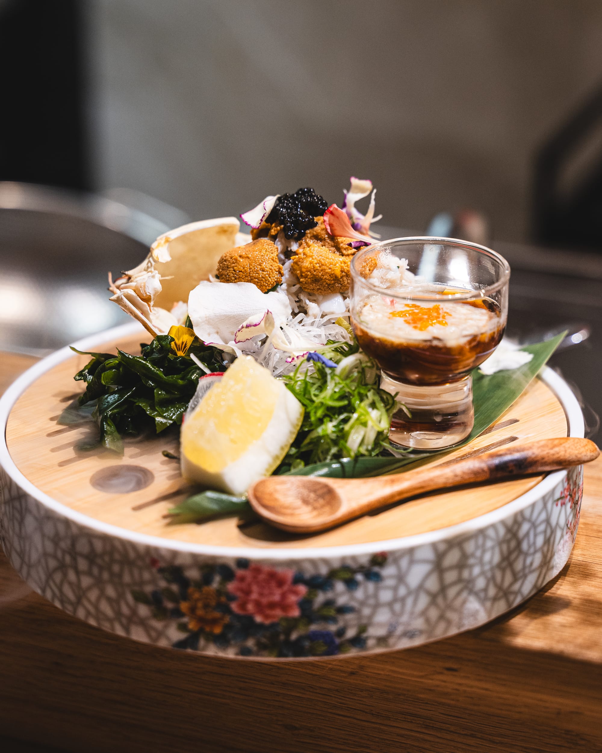 Close up of platter with lemon, uni, caviar and salad with a wooden spoon