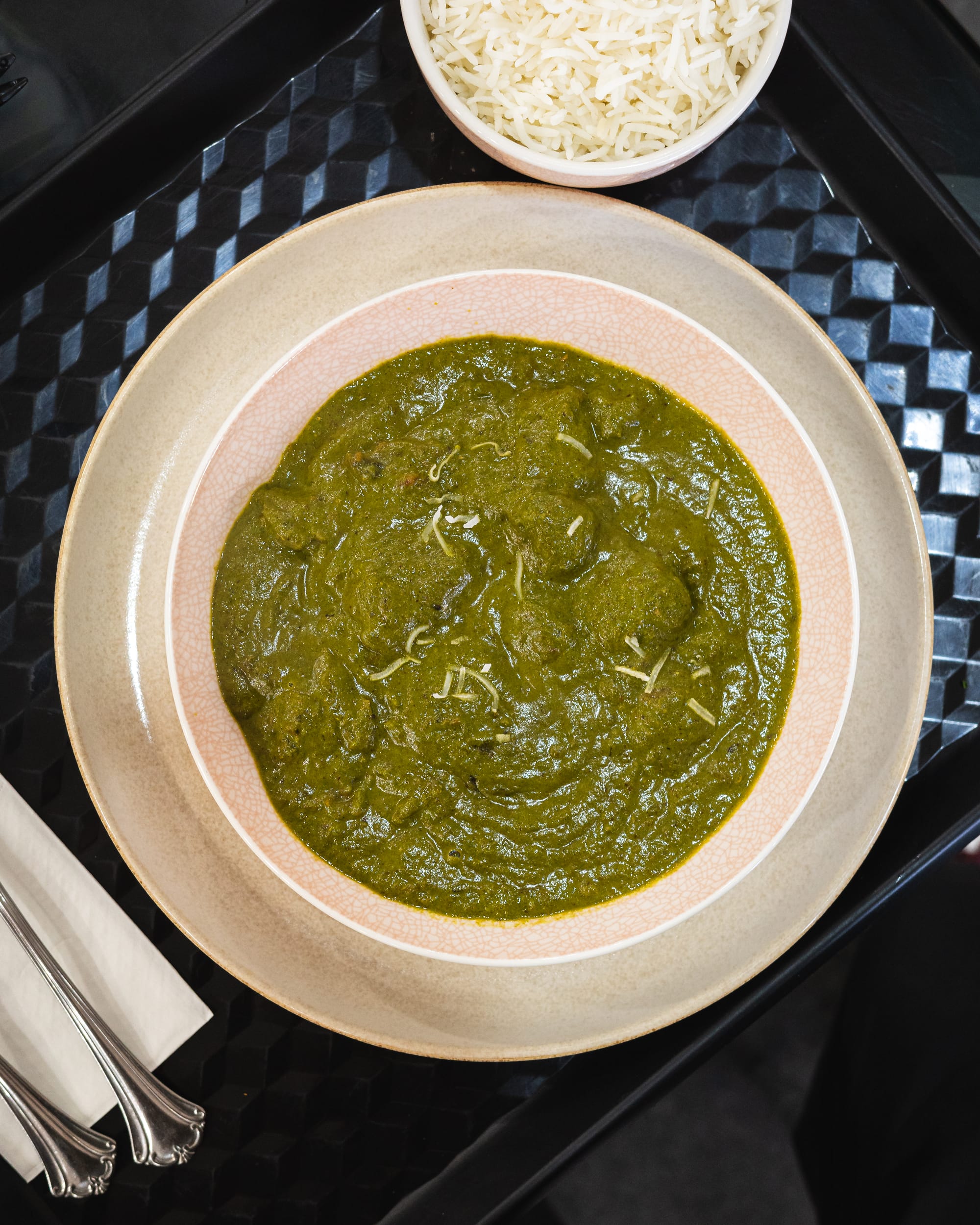 Top down shot of palak curry and a bowl of rice