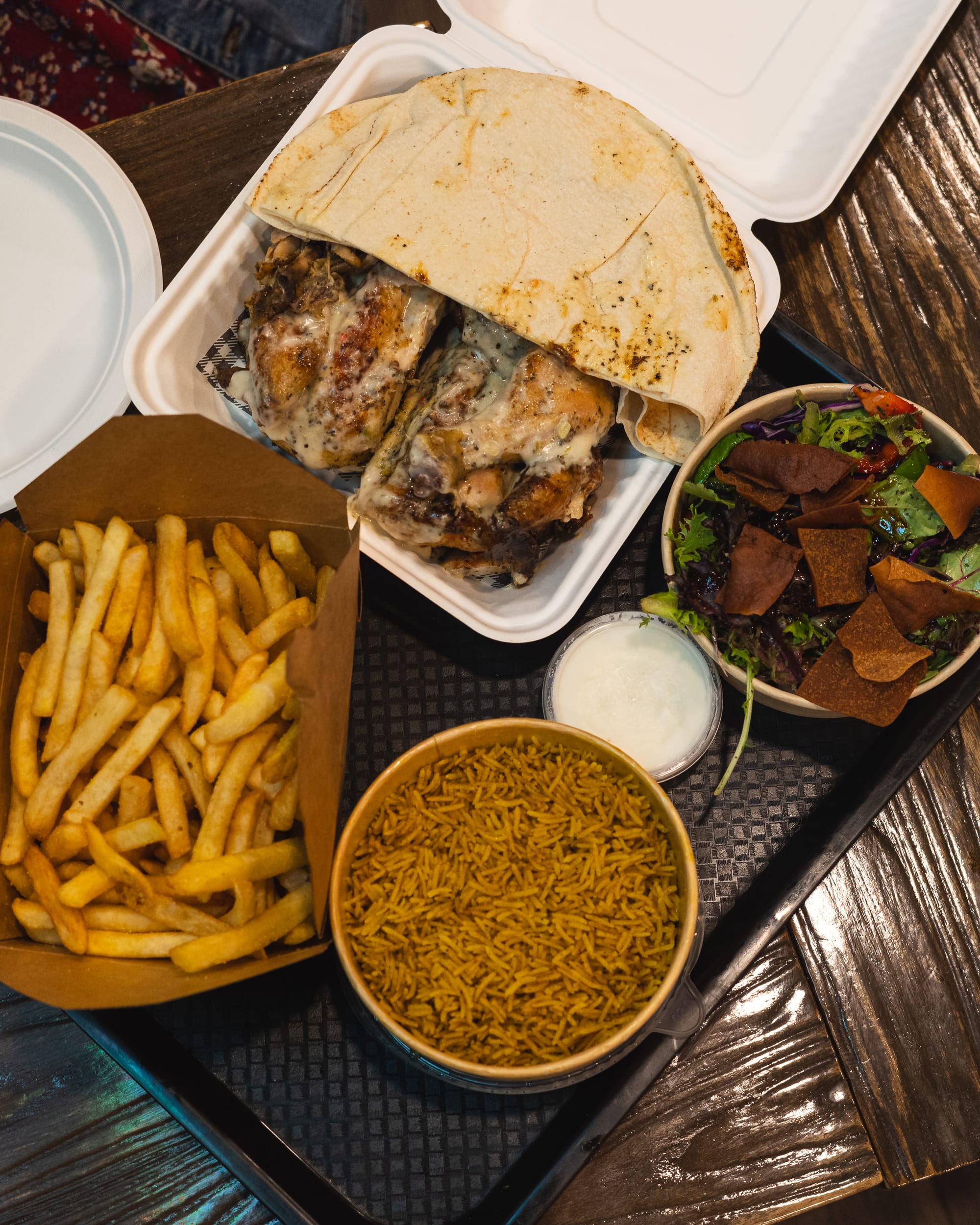 Top down shot of charcoal chicken, rice, salad, chips and garlic dip