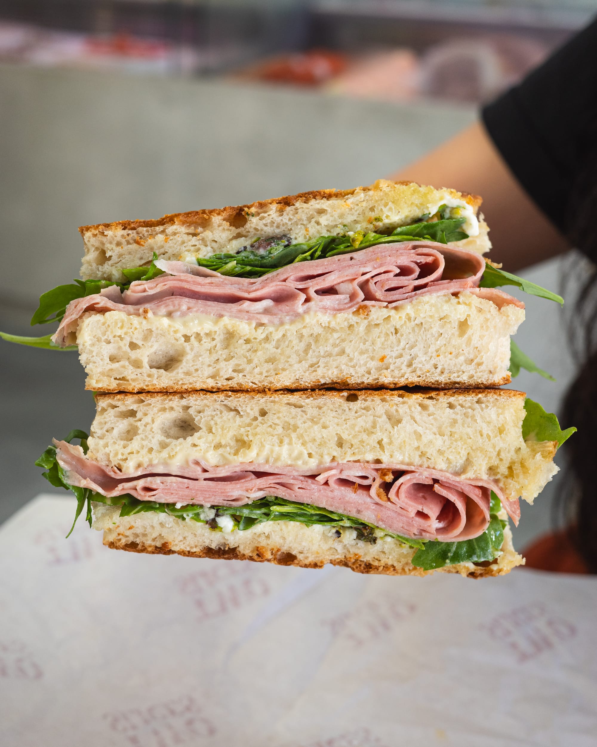 Hand holding sandwich with ham and lettuce