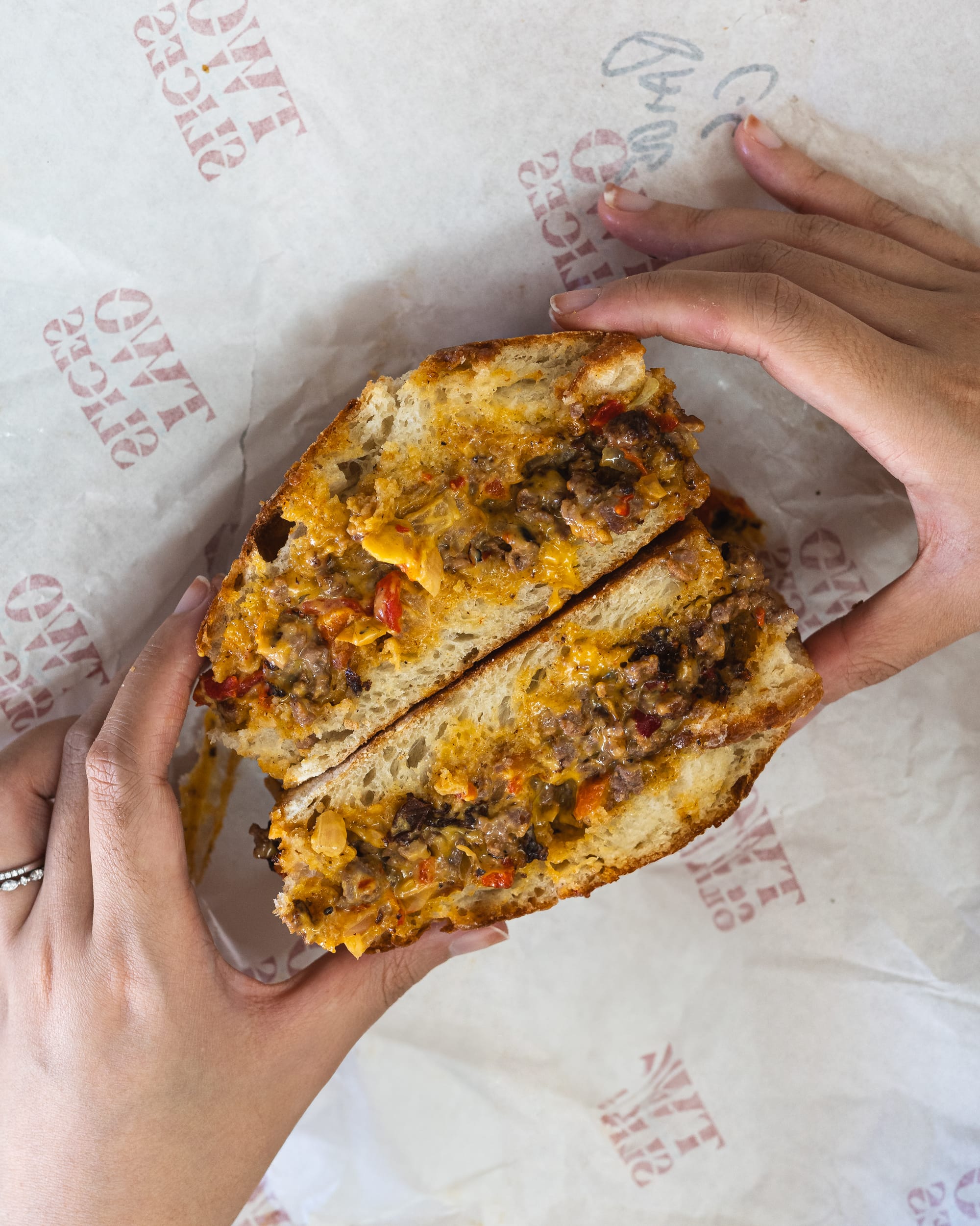 Top down shot of hand holding a sandwich with mince beef and cheese