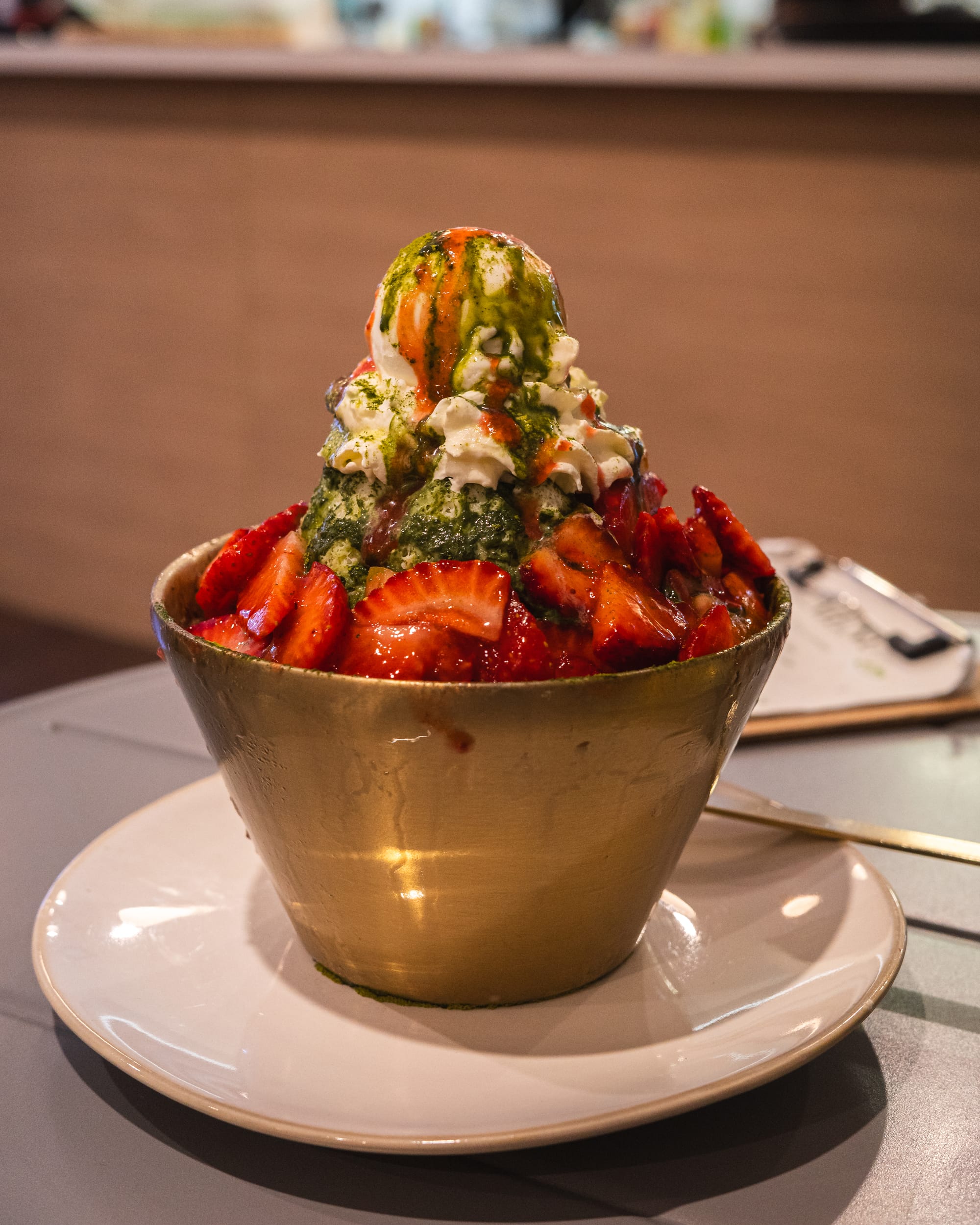 Another bowl of strawberry bingsu presented on a plate, viewed from a different angle.