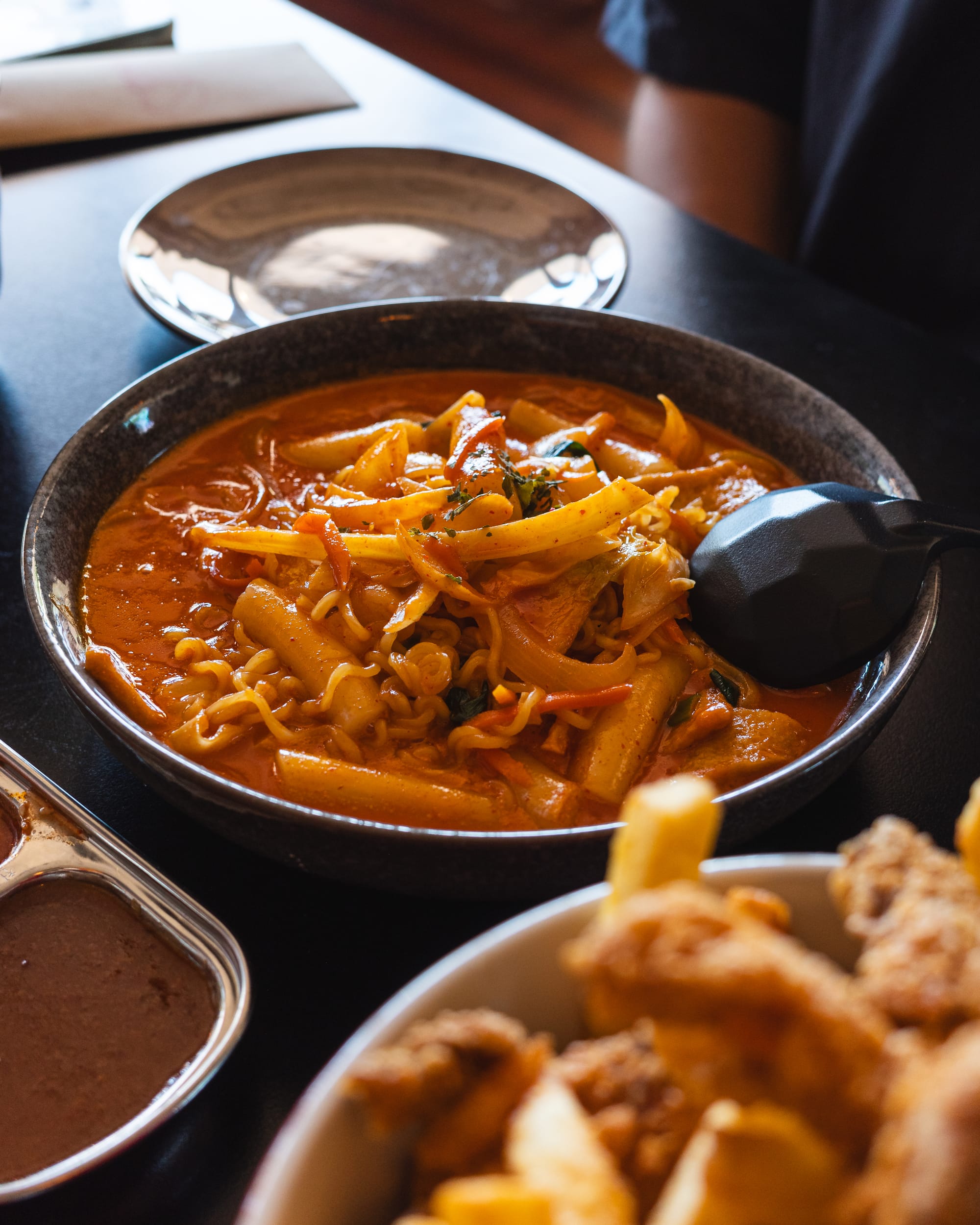 A hot stone pot filled with spicy soup containing vegetables and tofu.