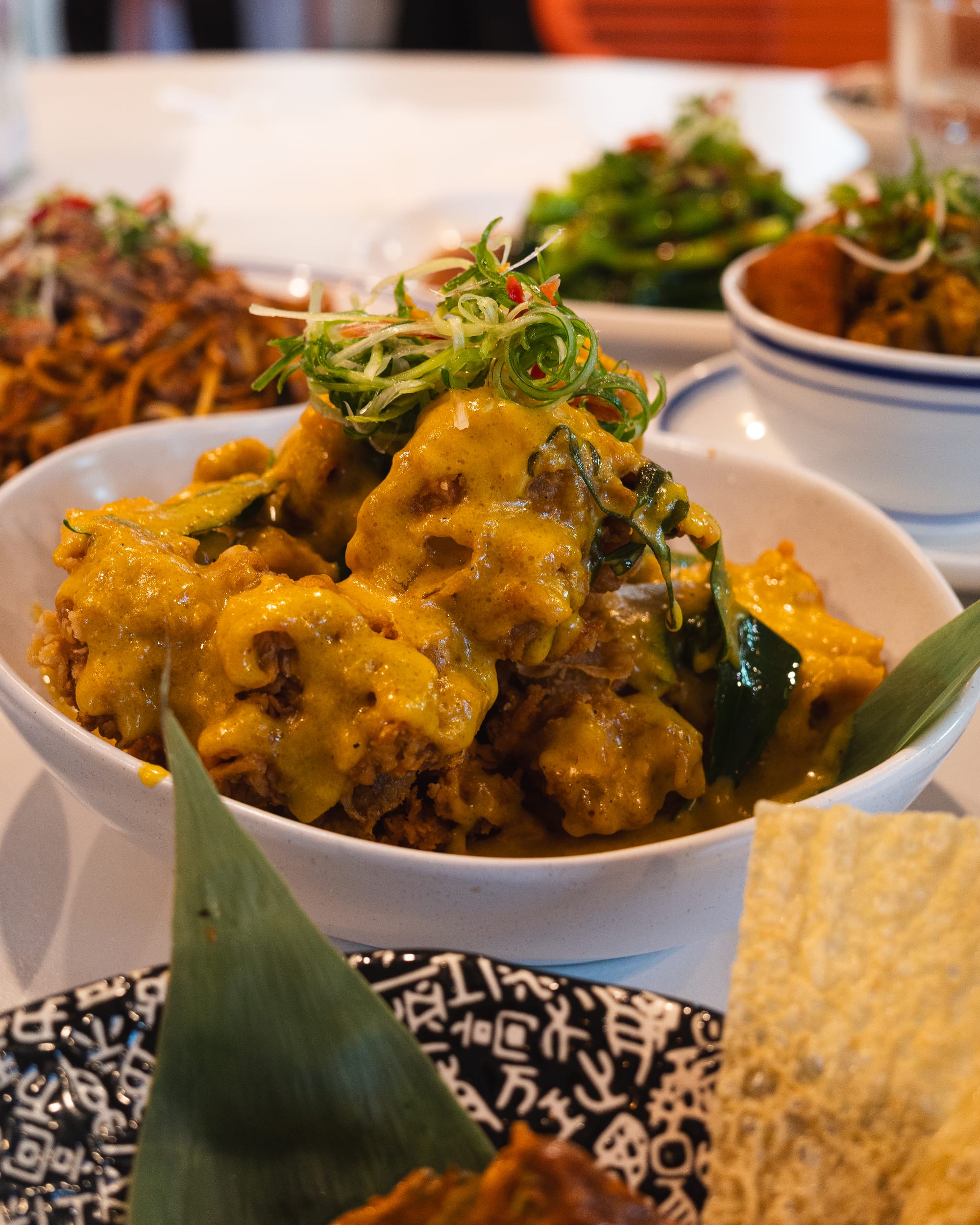 A plate of golden-brown fried chicken with sauce garnished with green onions.