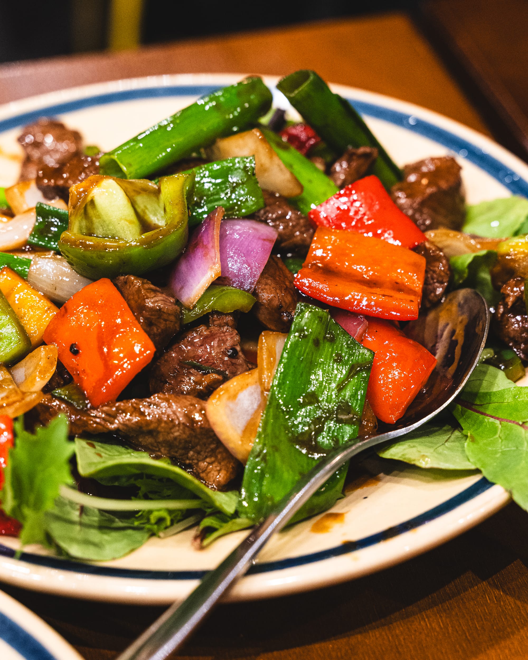 Close up of shaking beef stir fry with capsicum, spinach and onions