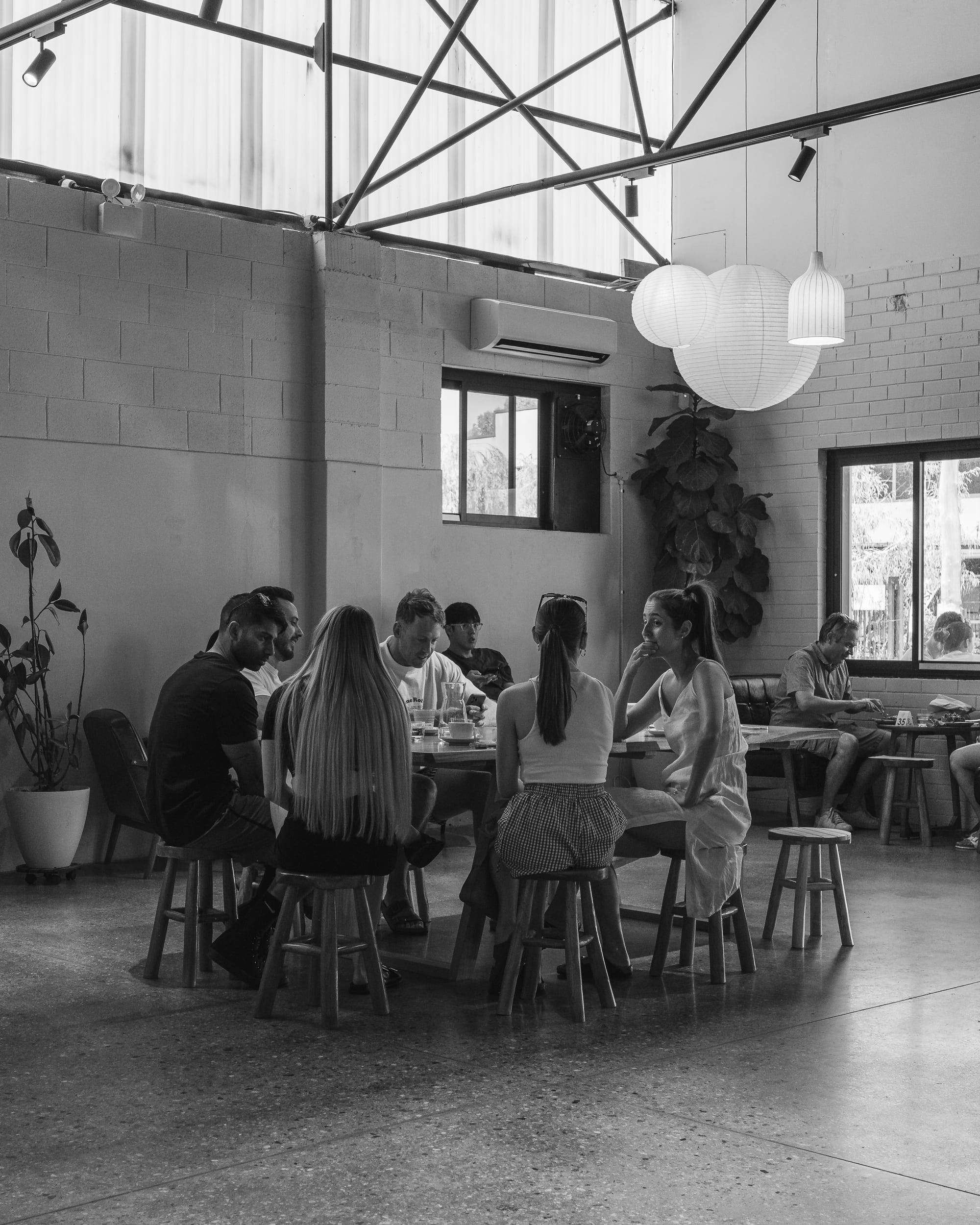 Black-and-white photo of a café interior with diners and pendant lights.