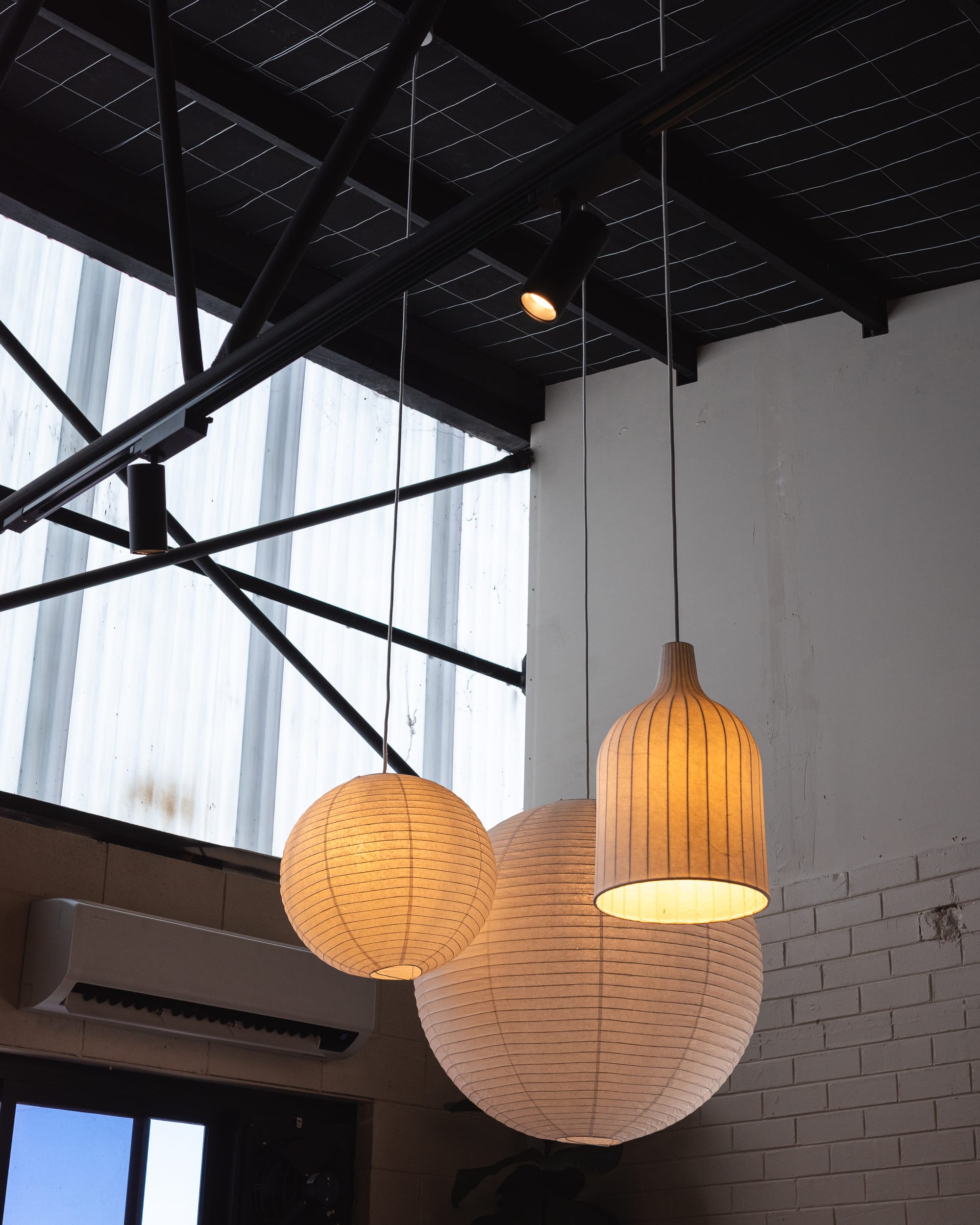 Modern café ceiling with large windows and hanging spherical light fixtures.