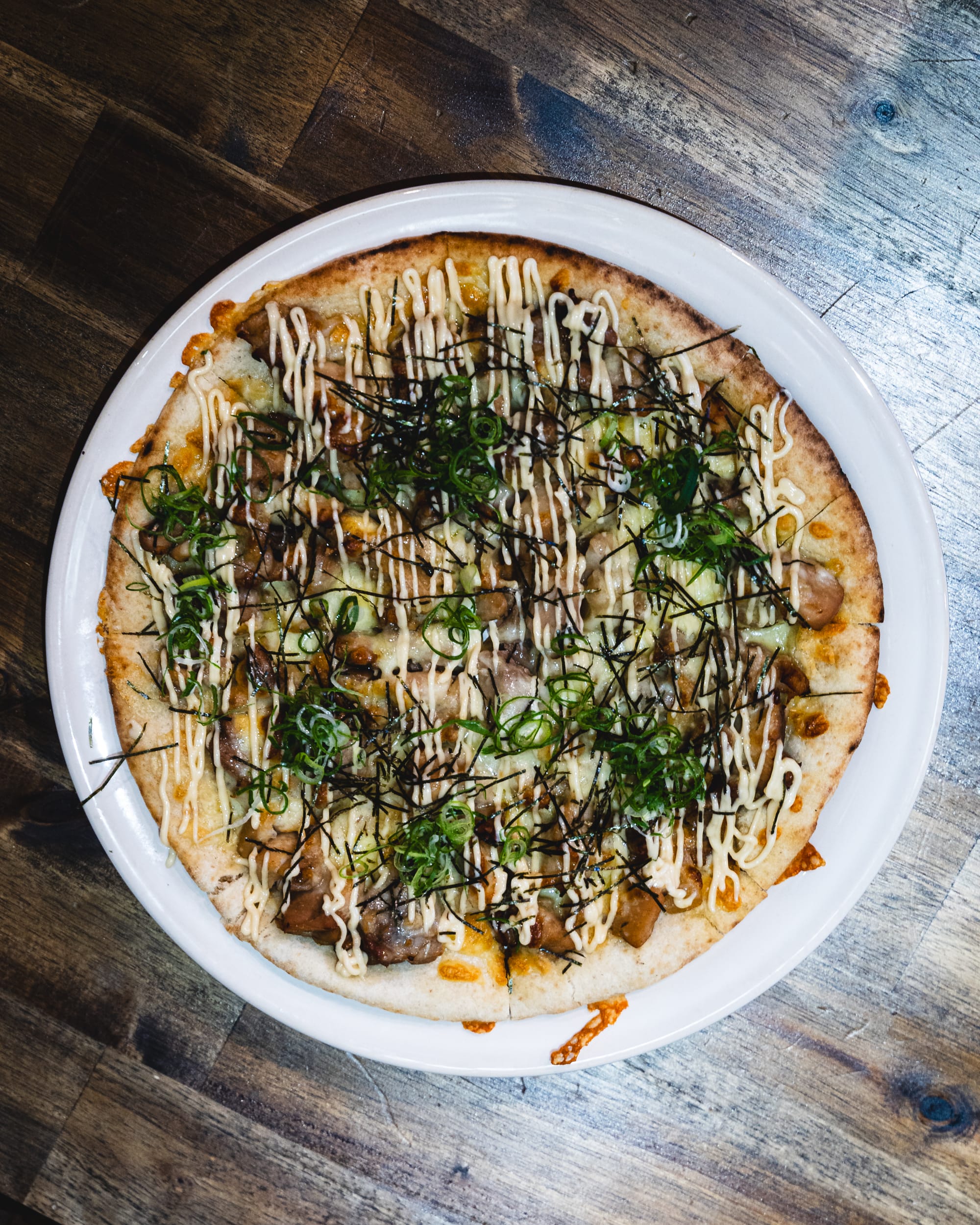 Thin-crust pizza with toppings of cheese, herbs, and olive oil drizzle.