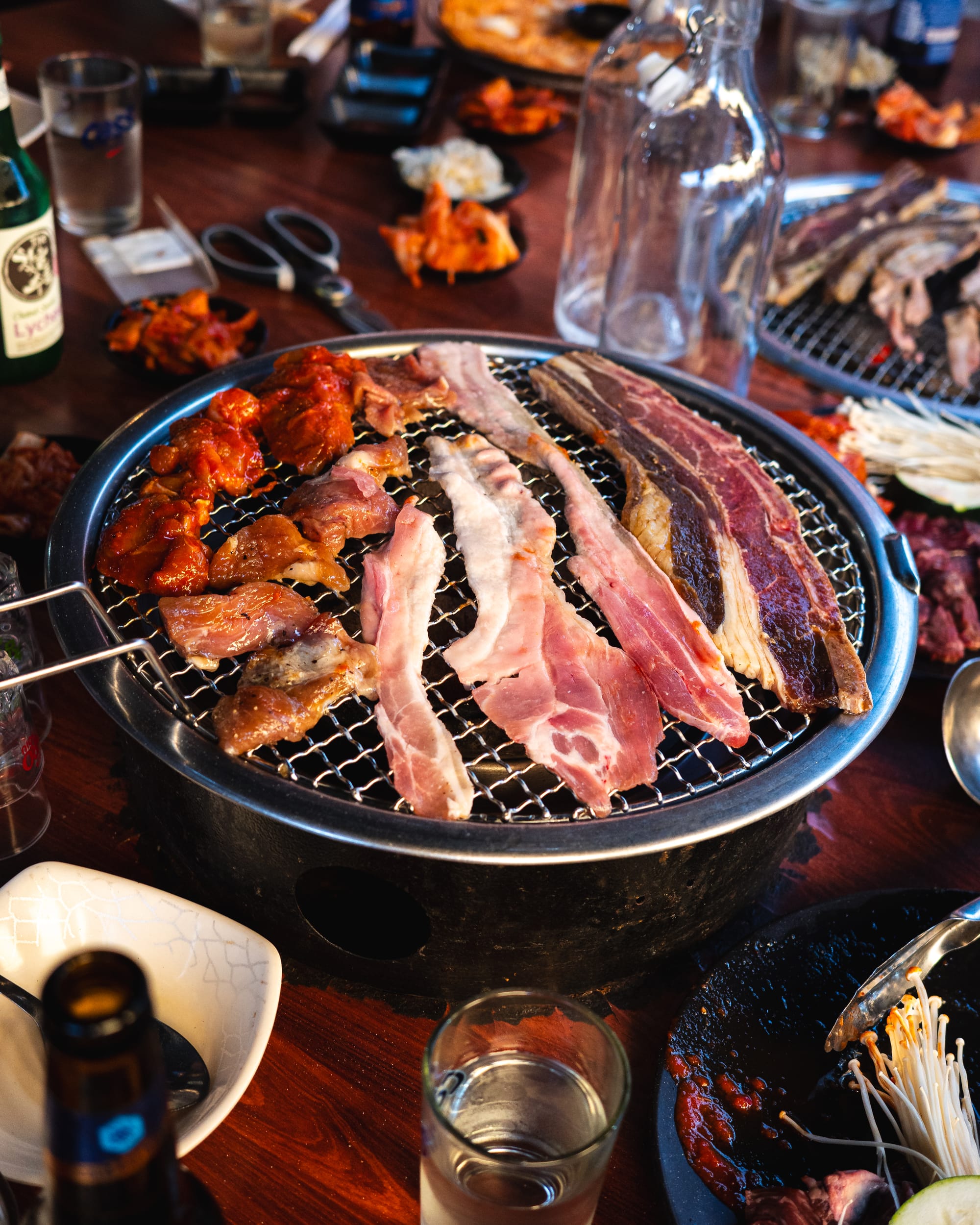 Korean barbecue with grilled meat on a tabletop grill surrounded by various side dishes